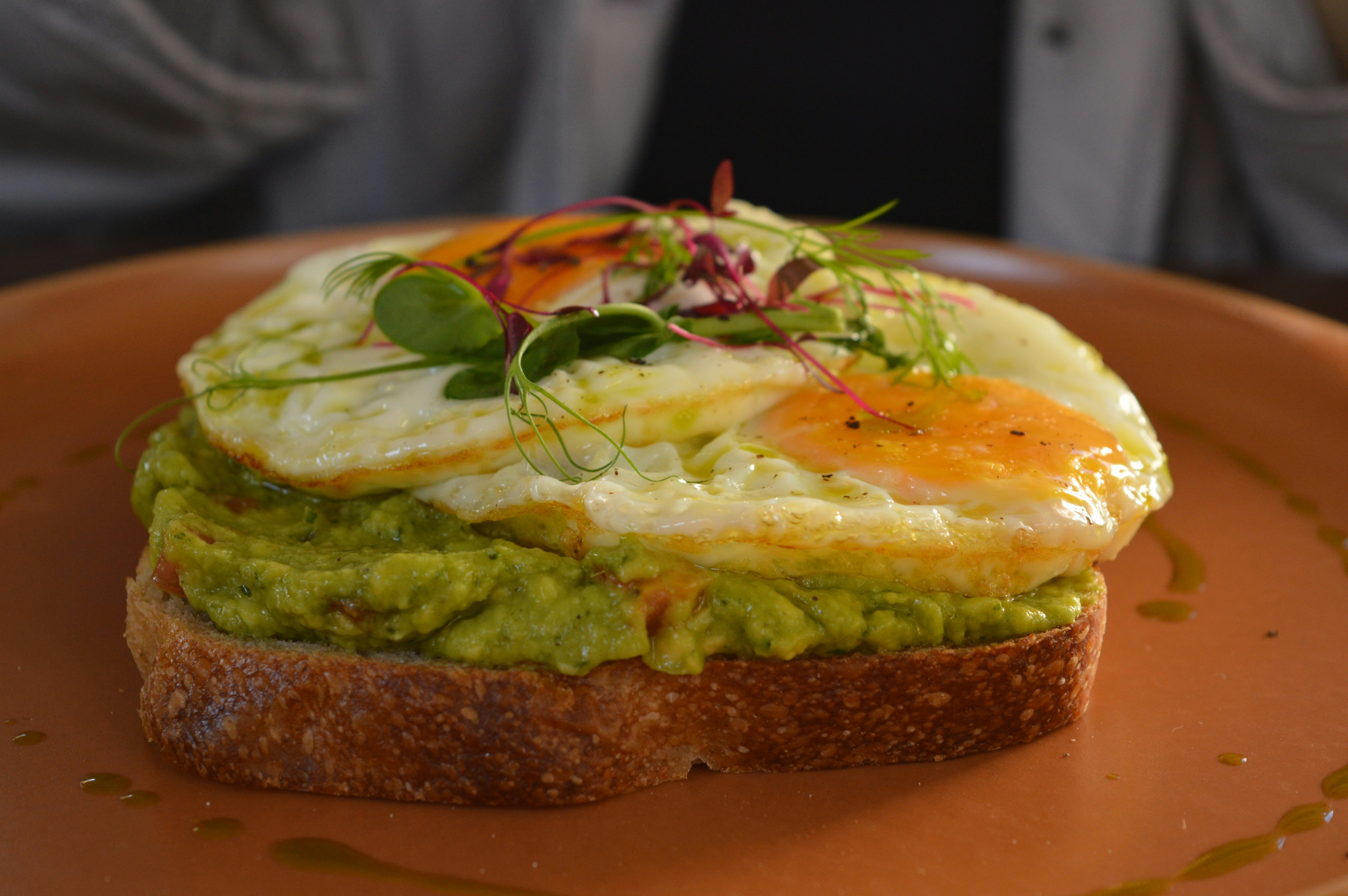 Avocado toast with two fried eggs and microgreens