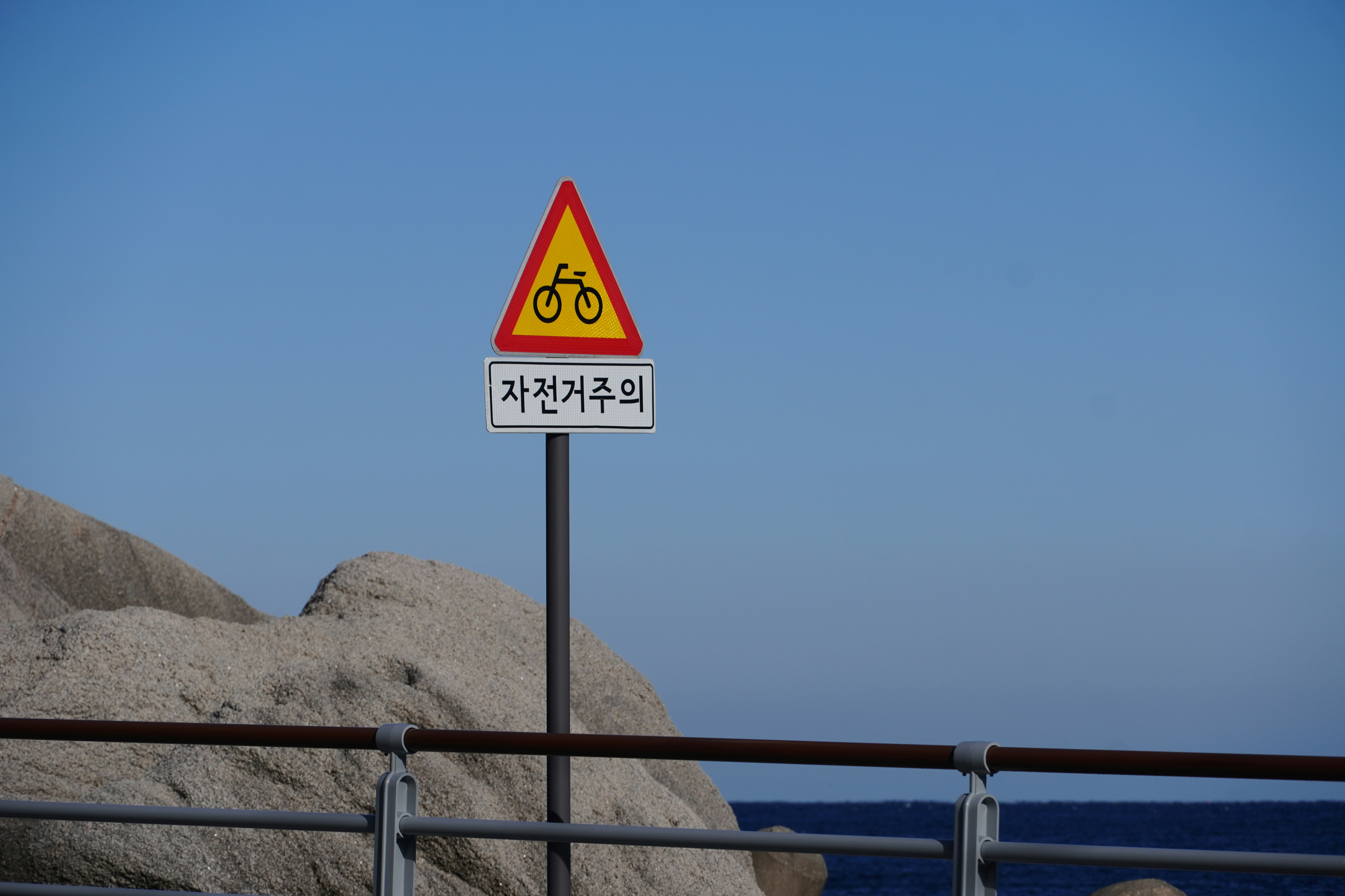 Bicycle warning sign against a clear blue sky