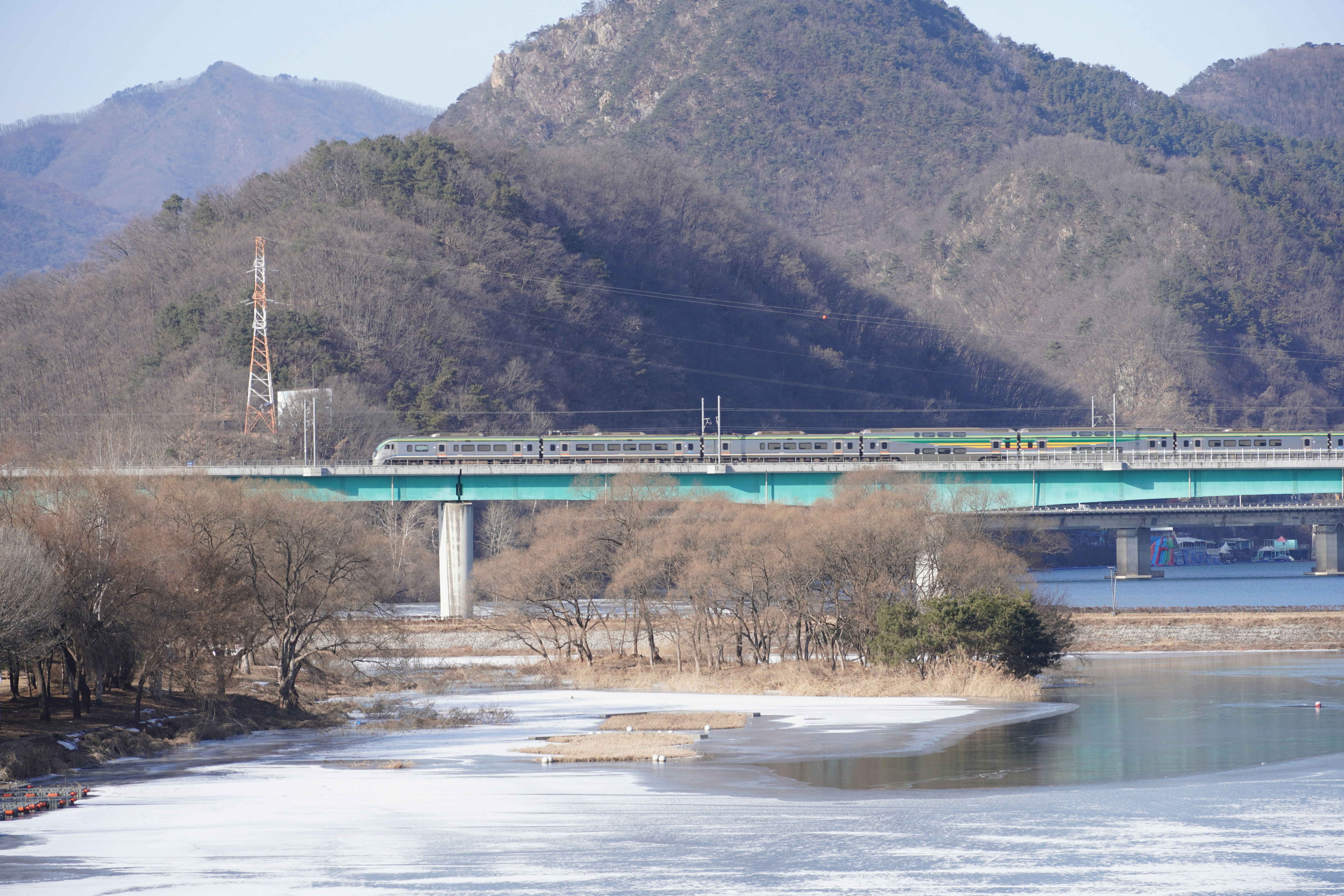 Train crossing a bridge over a frozen river.