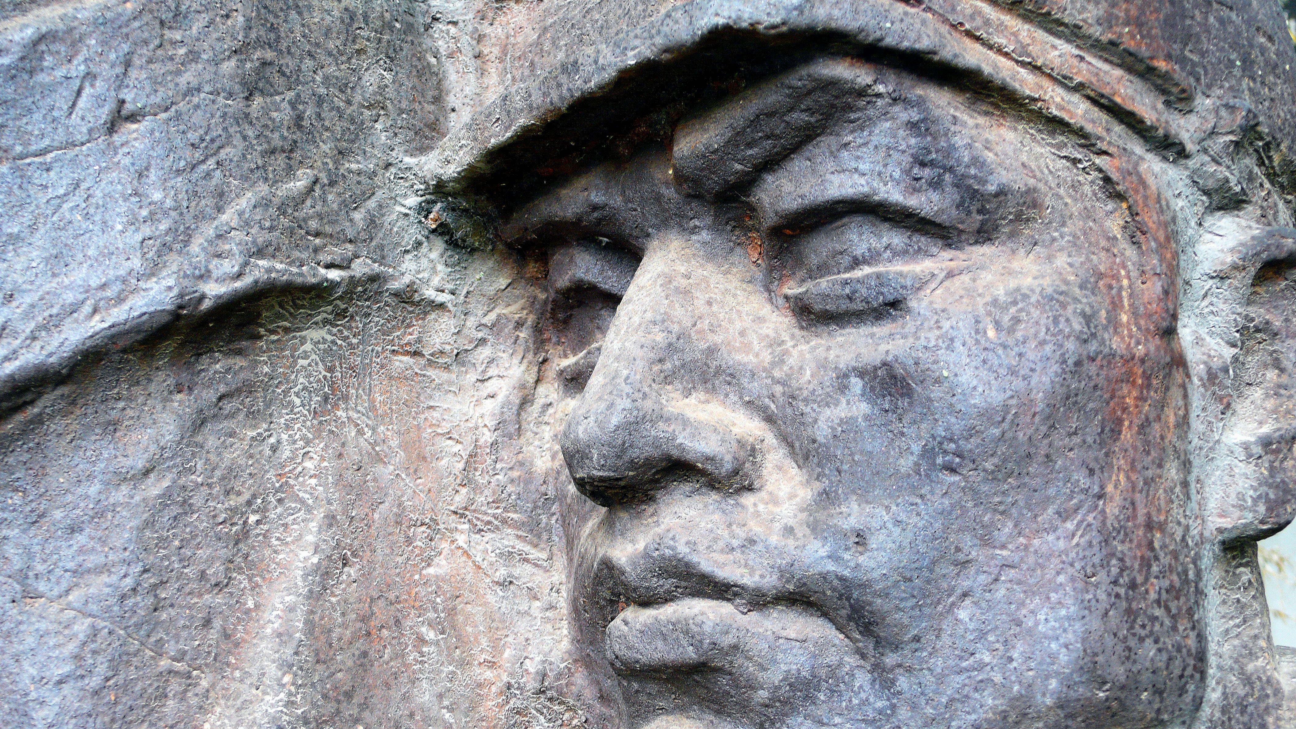 Close-up of a weathered stone carving of a man's face.