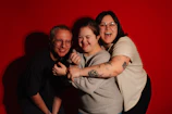 Three friends embracing happily against a red background