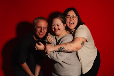 Three friends embracing happily against a red background