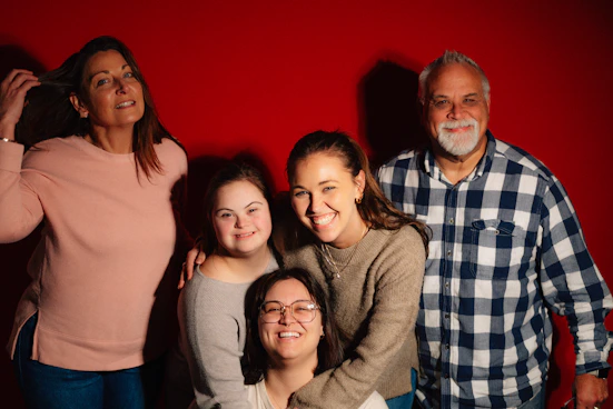 A family poses for a portrait against a red background.