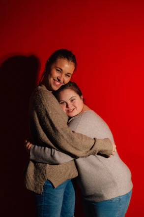 Two women hugging against a red background