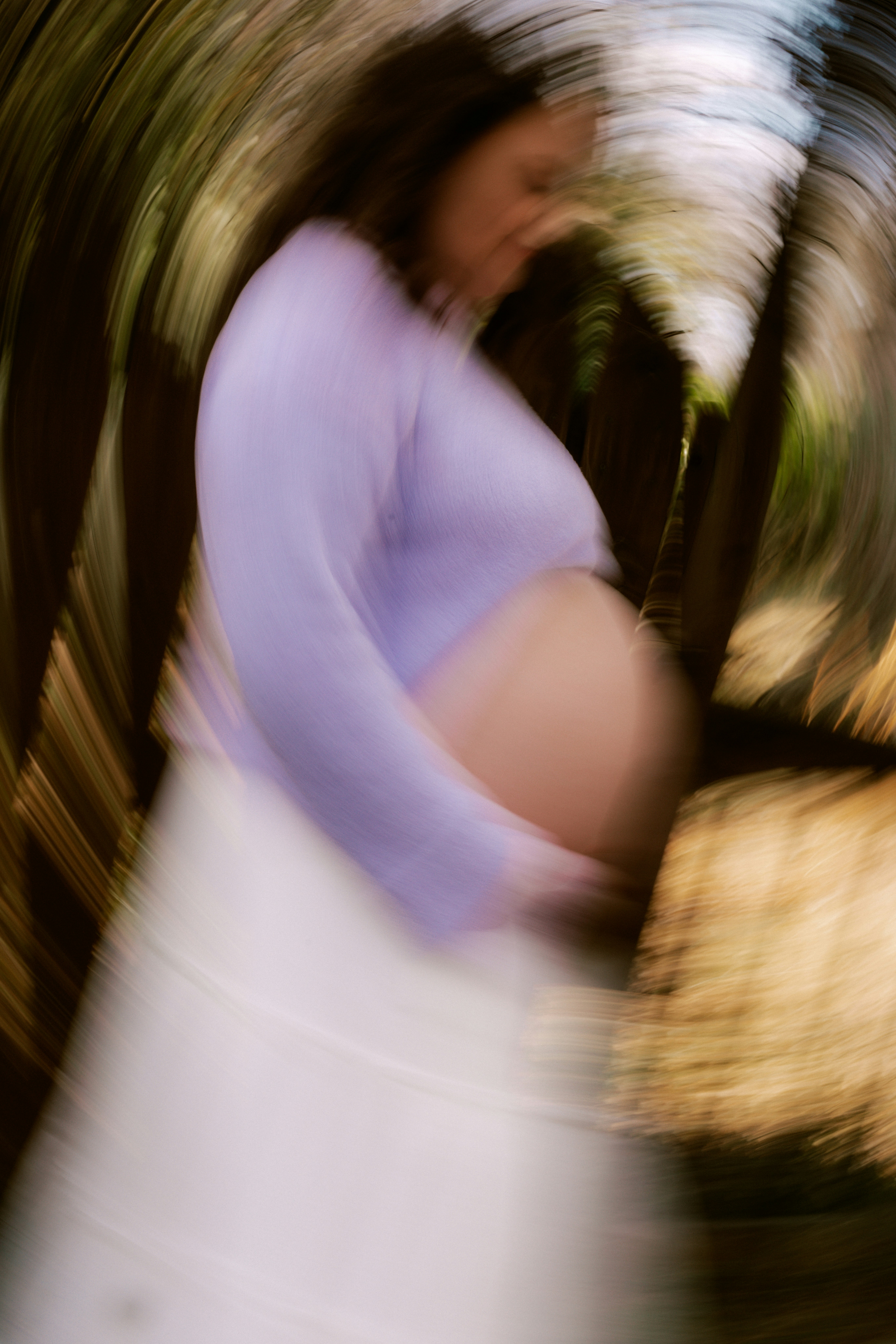 Pregnant woman in a lavender top holding belly