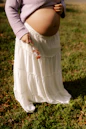 Pregnant woman in a white skirt holding berries.