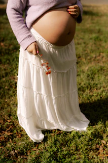 Pregnant woman in a white skirt holding berries.