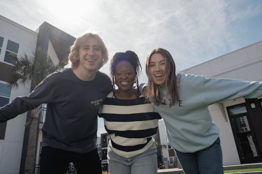 Three smiling friends with arms around each other
