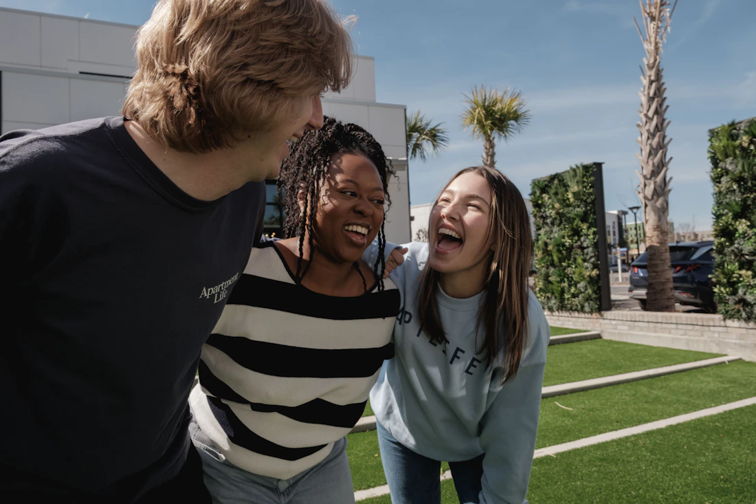 Drei Freunde lachen gemeinsam im Freien als Symbol für Unterstützung und soziale Situationen