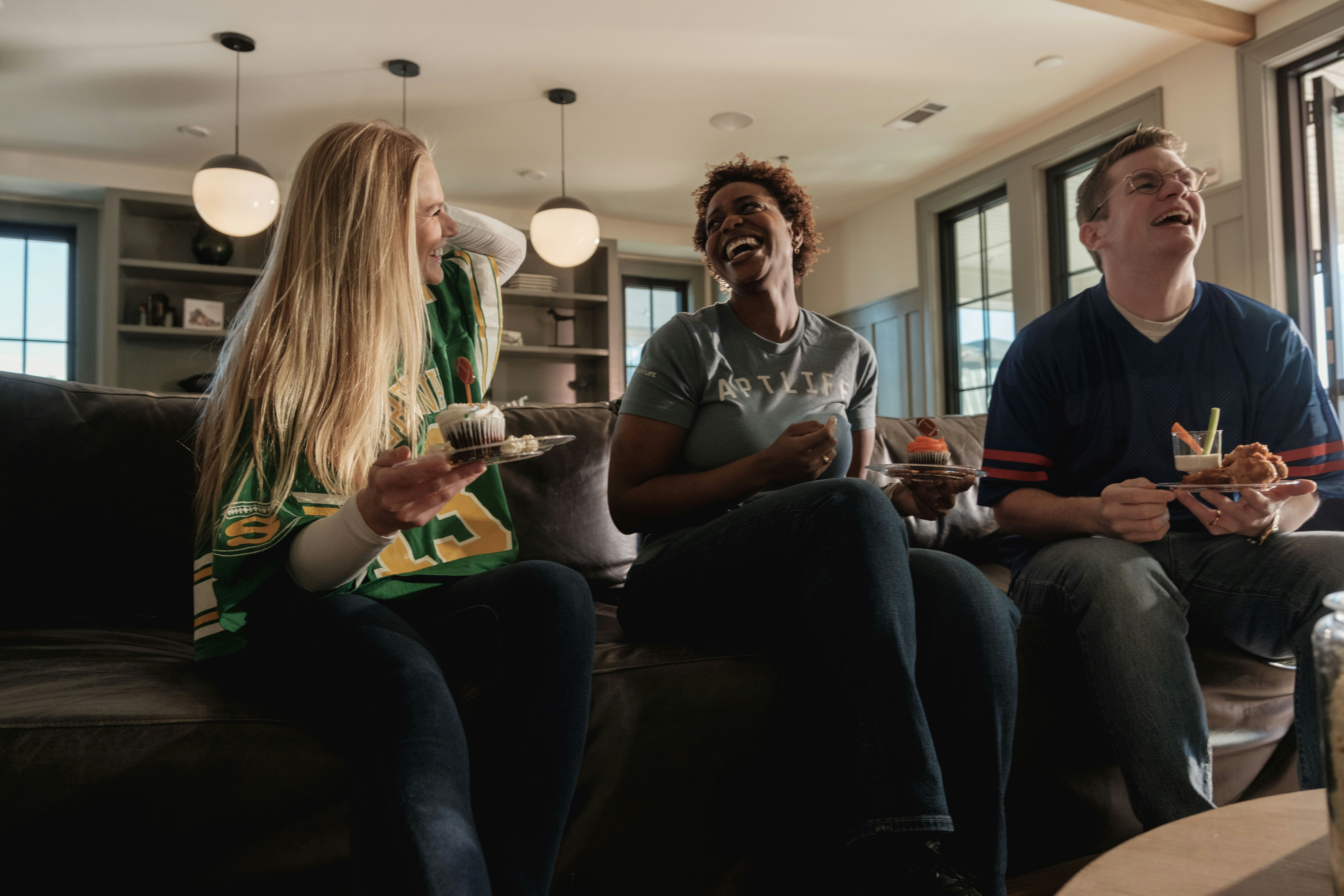 Grupo de personas viendo un programa de televisión y reaccionando a una escena tensa
