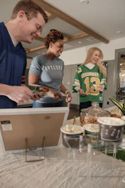 Friends in jerseys gathered around a table with snacks.