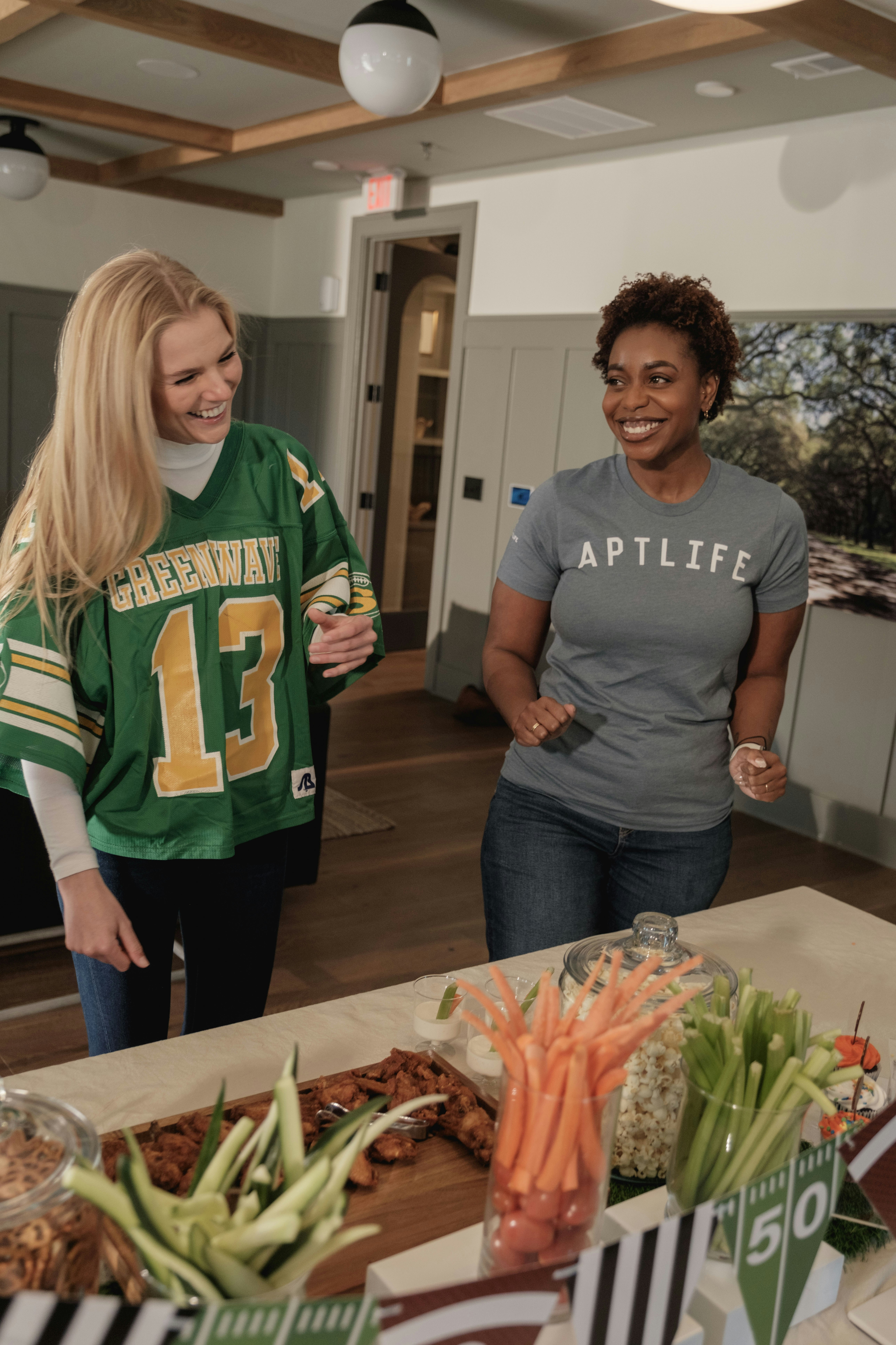 Two women smiling near a table with snacks