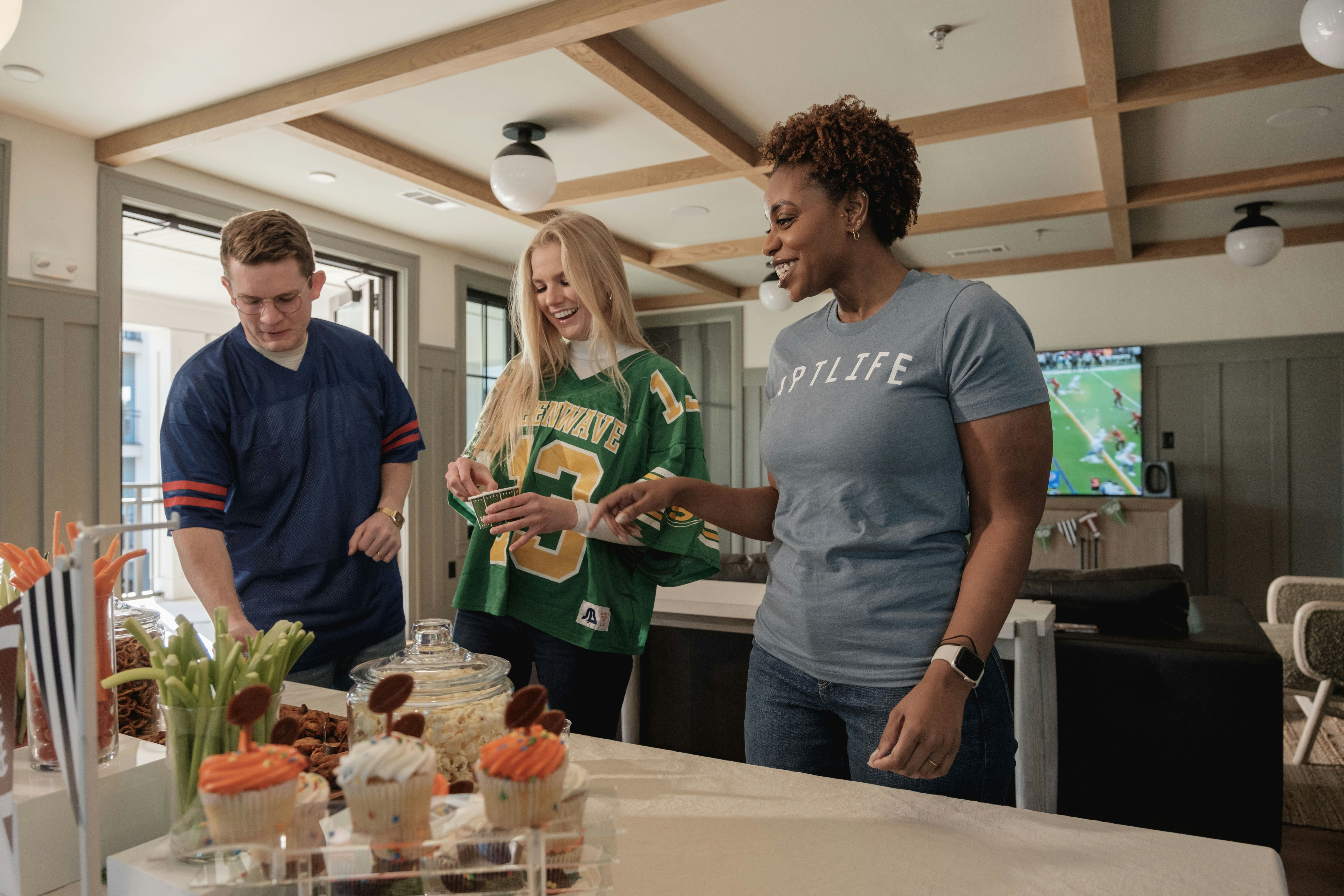 Three friends gather around a table with snacks