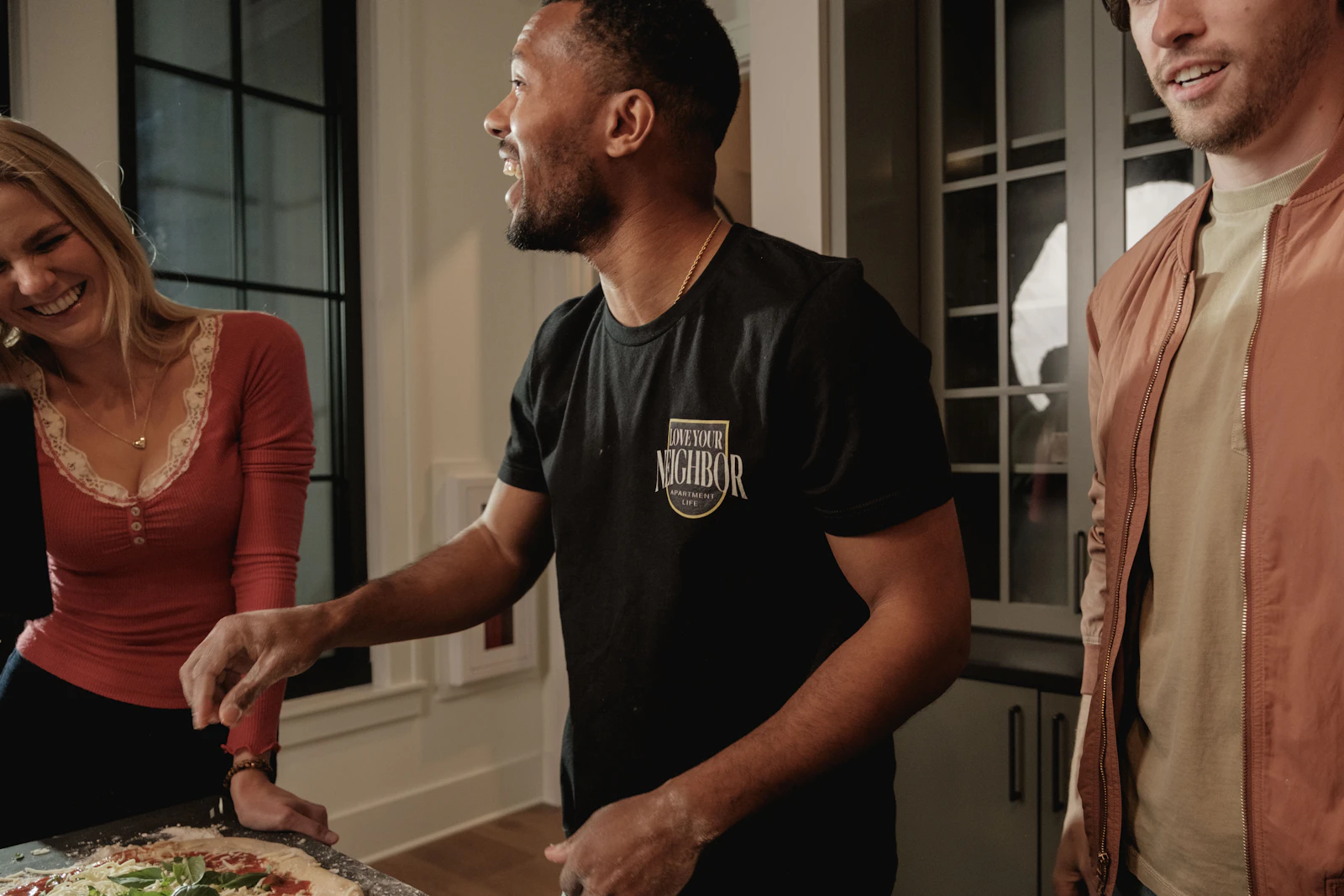 Housemates laughing while making pizza together
