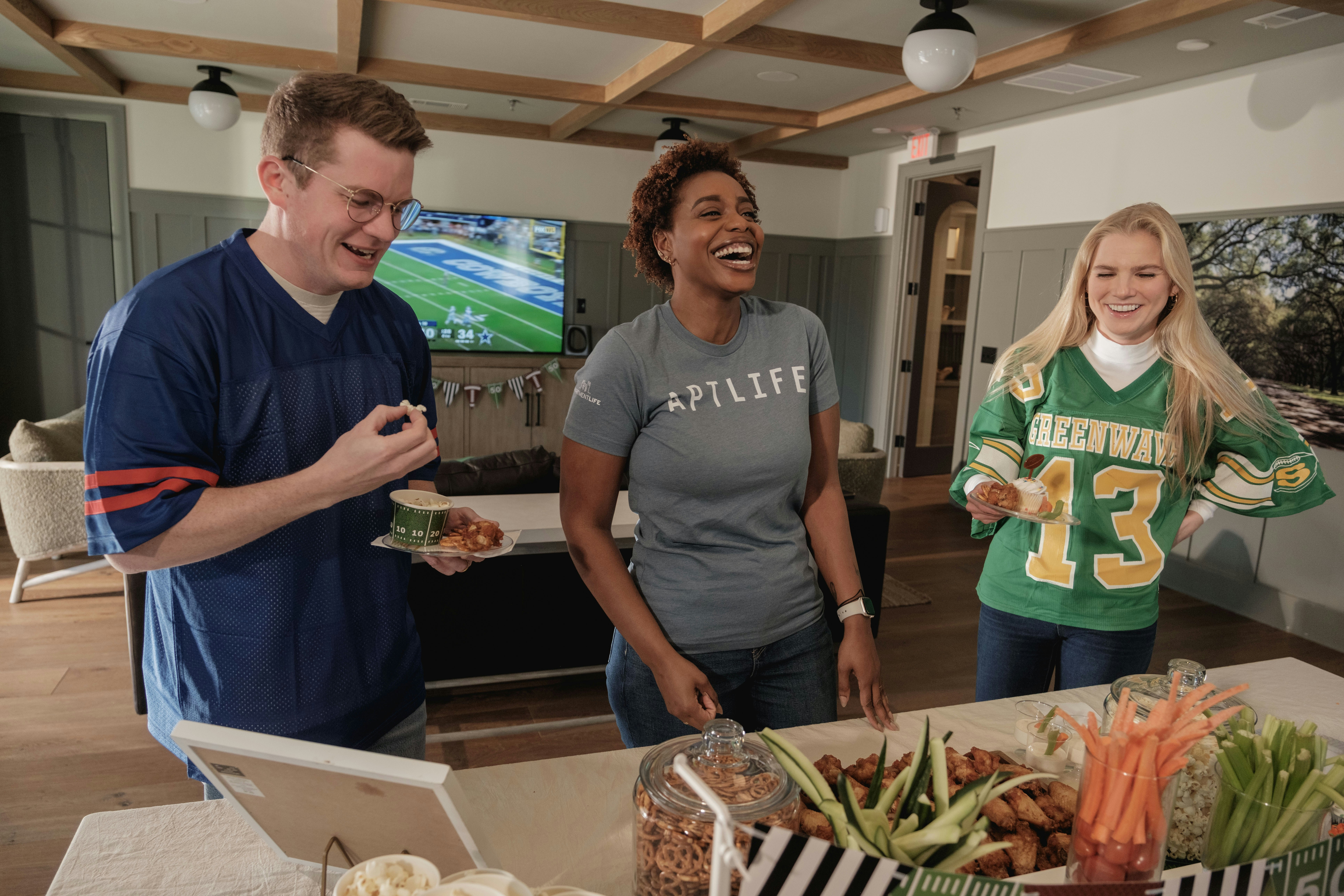 Friends laughing and eating snacks watching a game