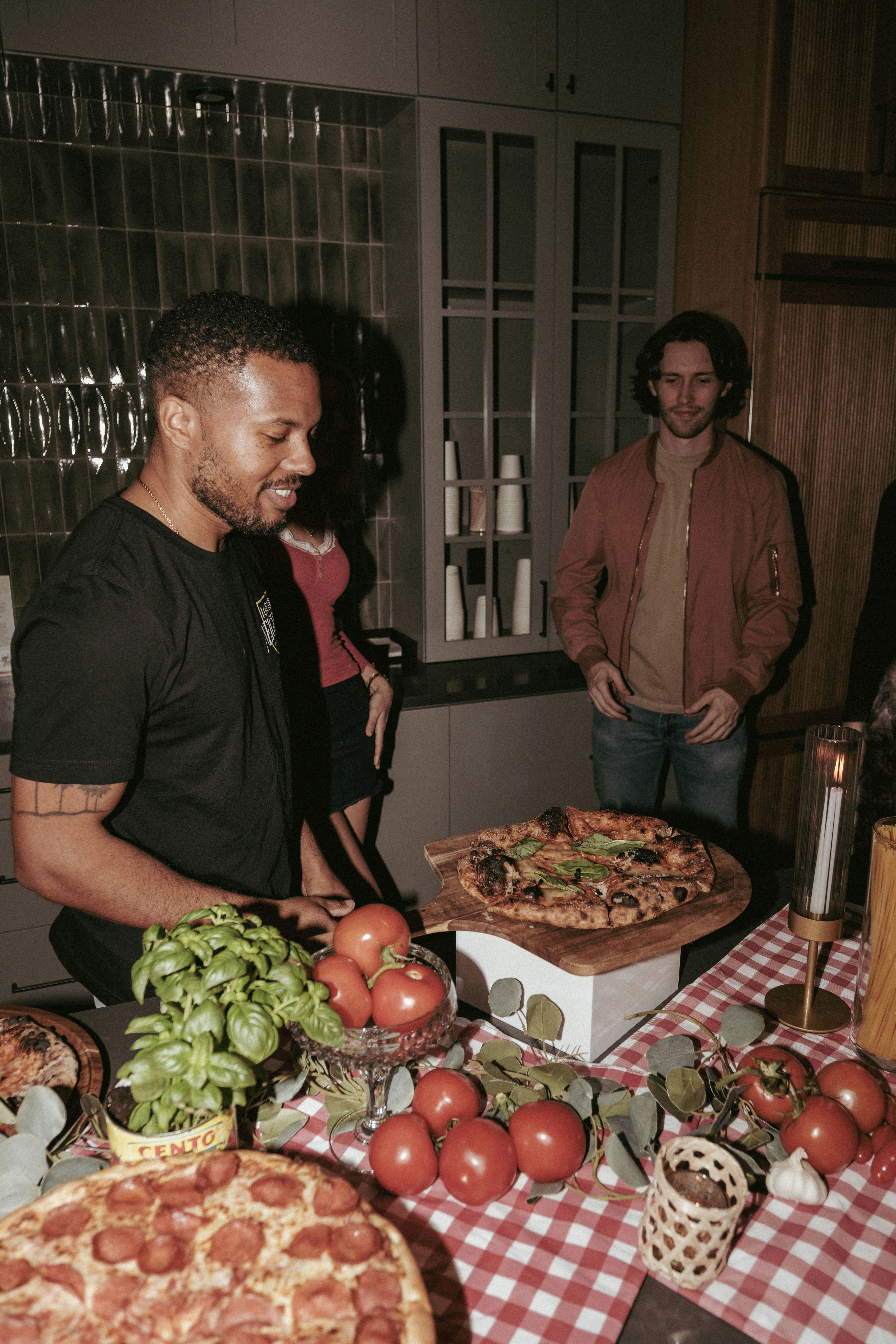 People gathered around a table with pizzas and fresh ingredients.