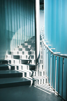 Sunlight streams down a modern spiral staircase