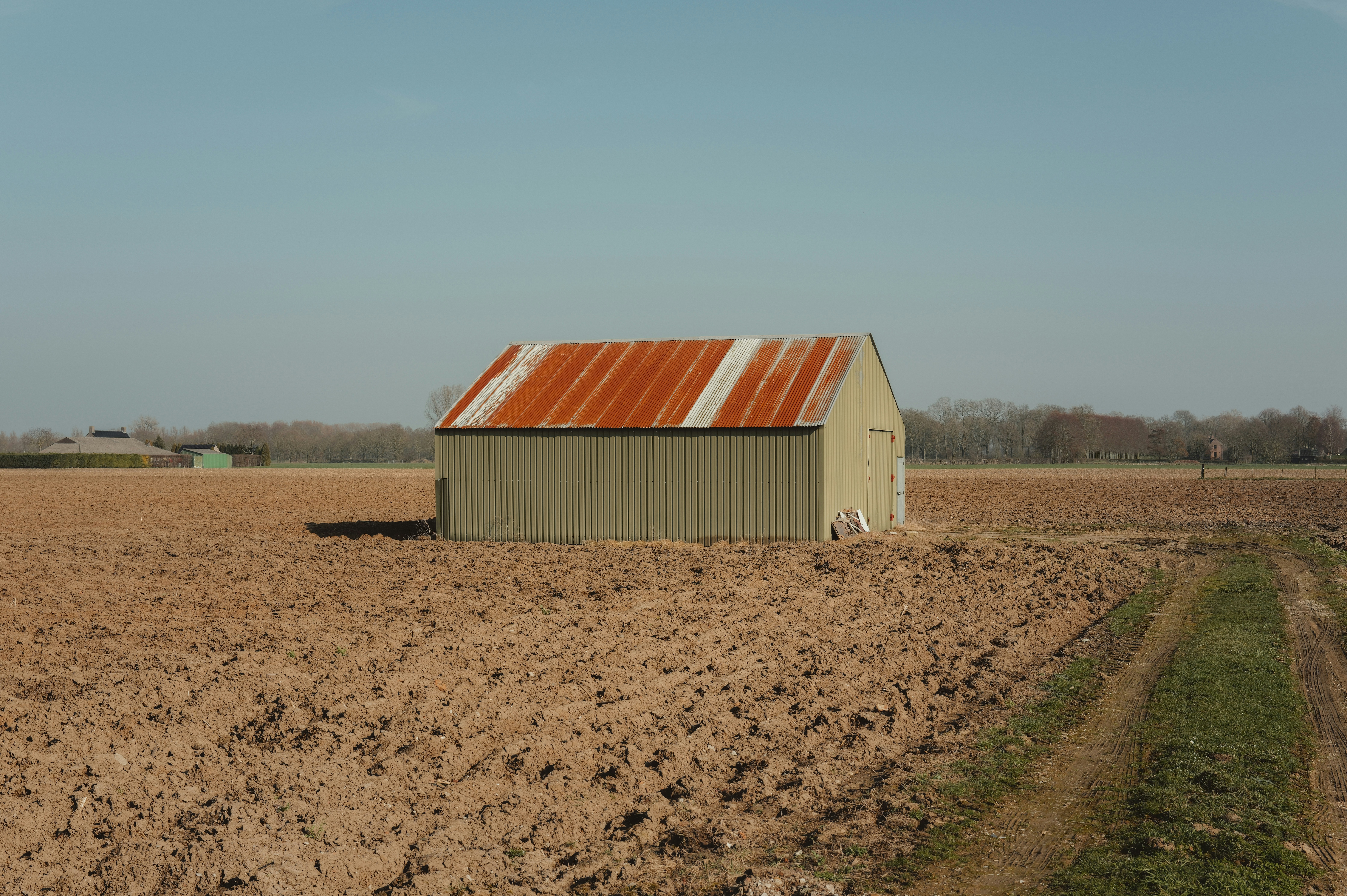 Small barn with rusty roof in a dry field