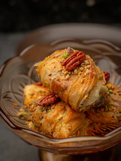 Sweet baklava pastry with nuts in a glass bowl.