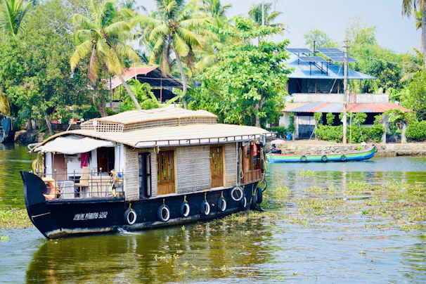 A houseboat floats on a calm river surrounded by greenery.