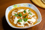 A bowl of creamy chicken tikka masala with mint leaves
