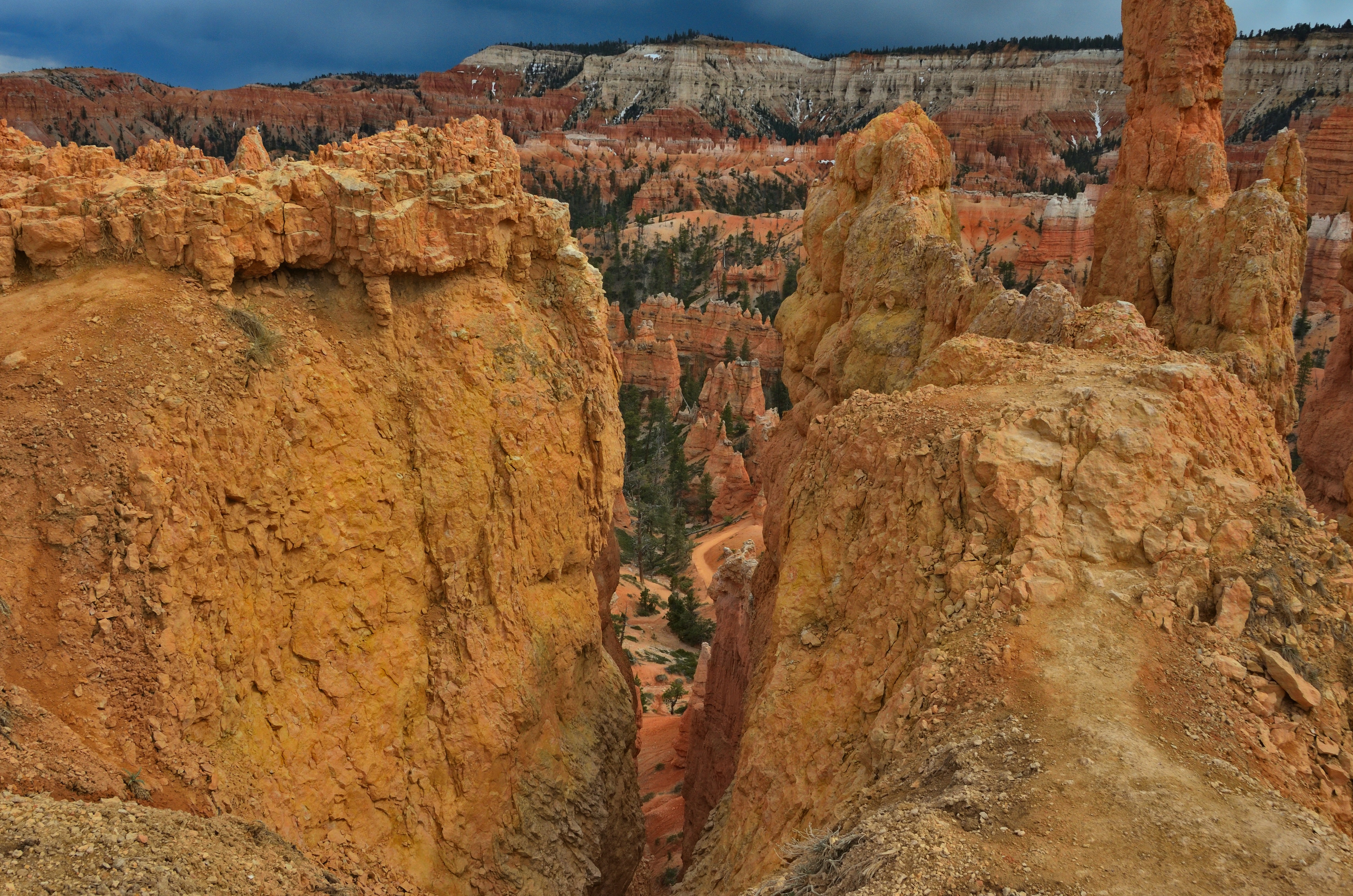 Orange rock formations in a canyon under a cloudy sky