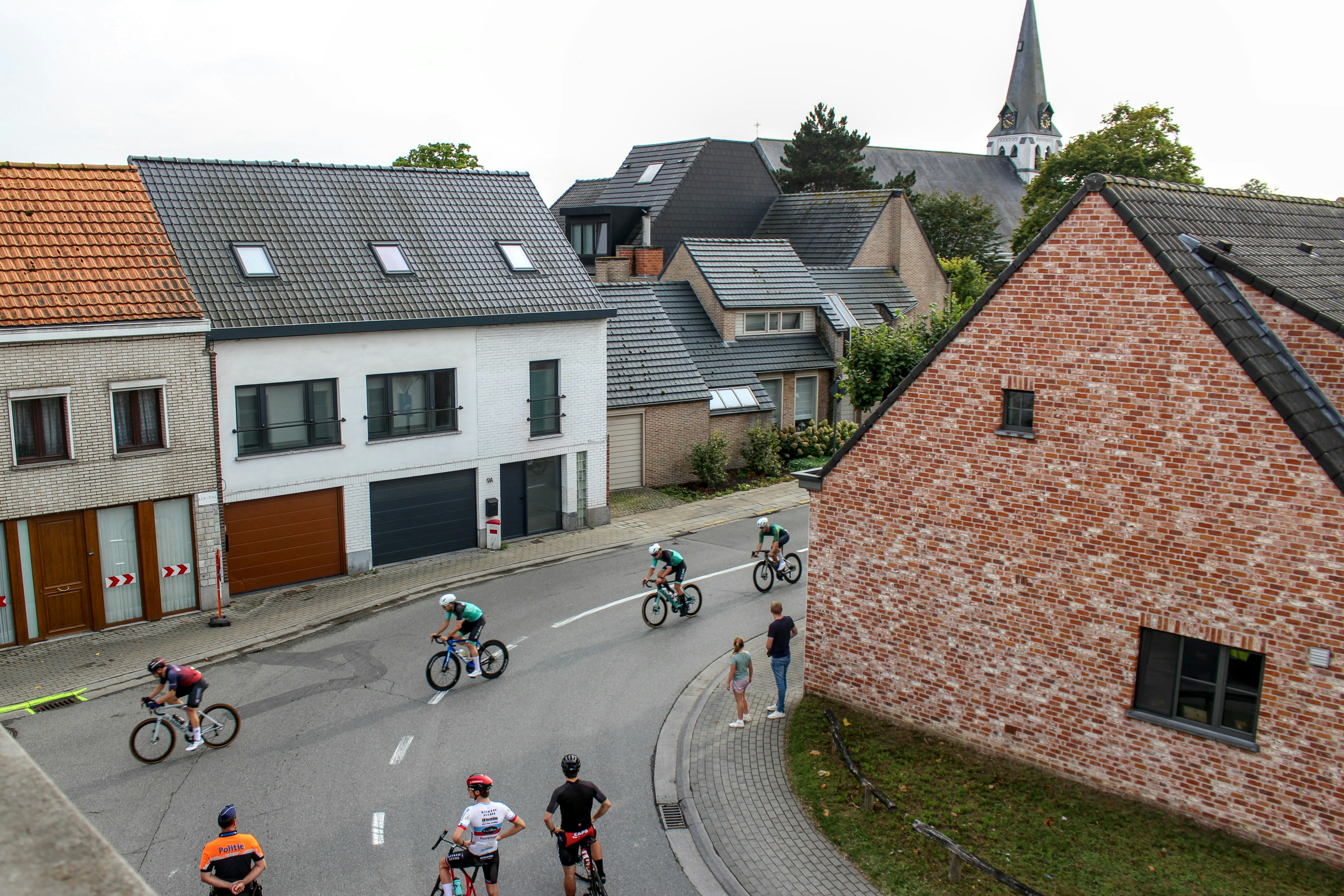 Cyclists race down a street in a european village.