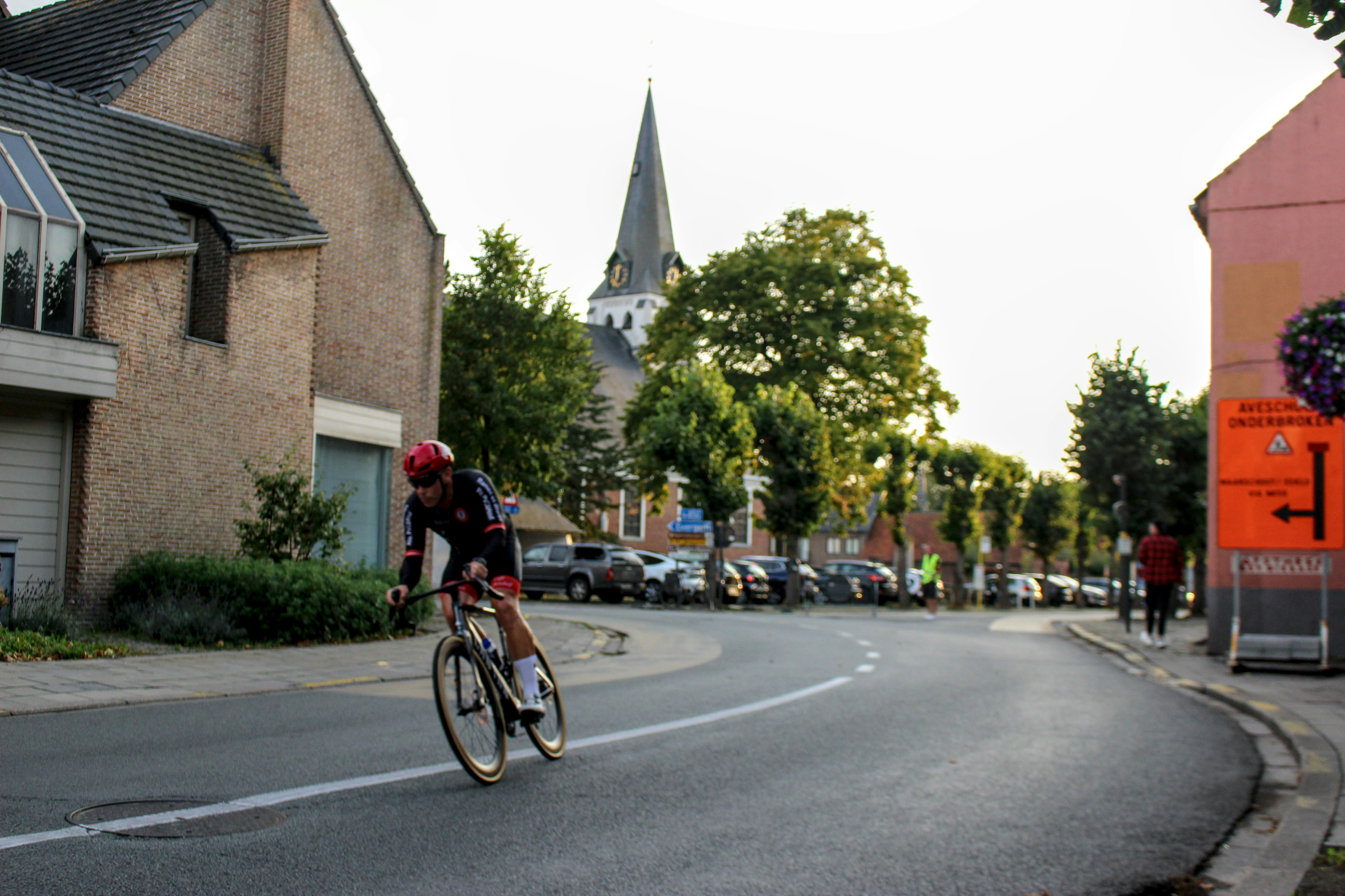 Cyclist races down a street with buildings and church.