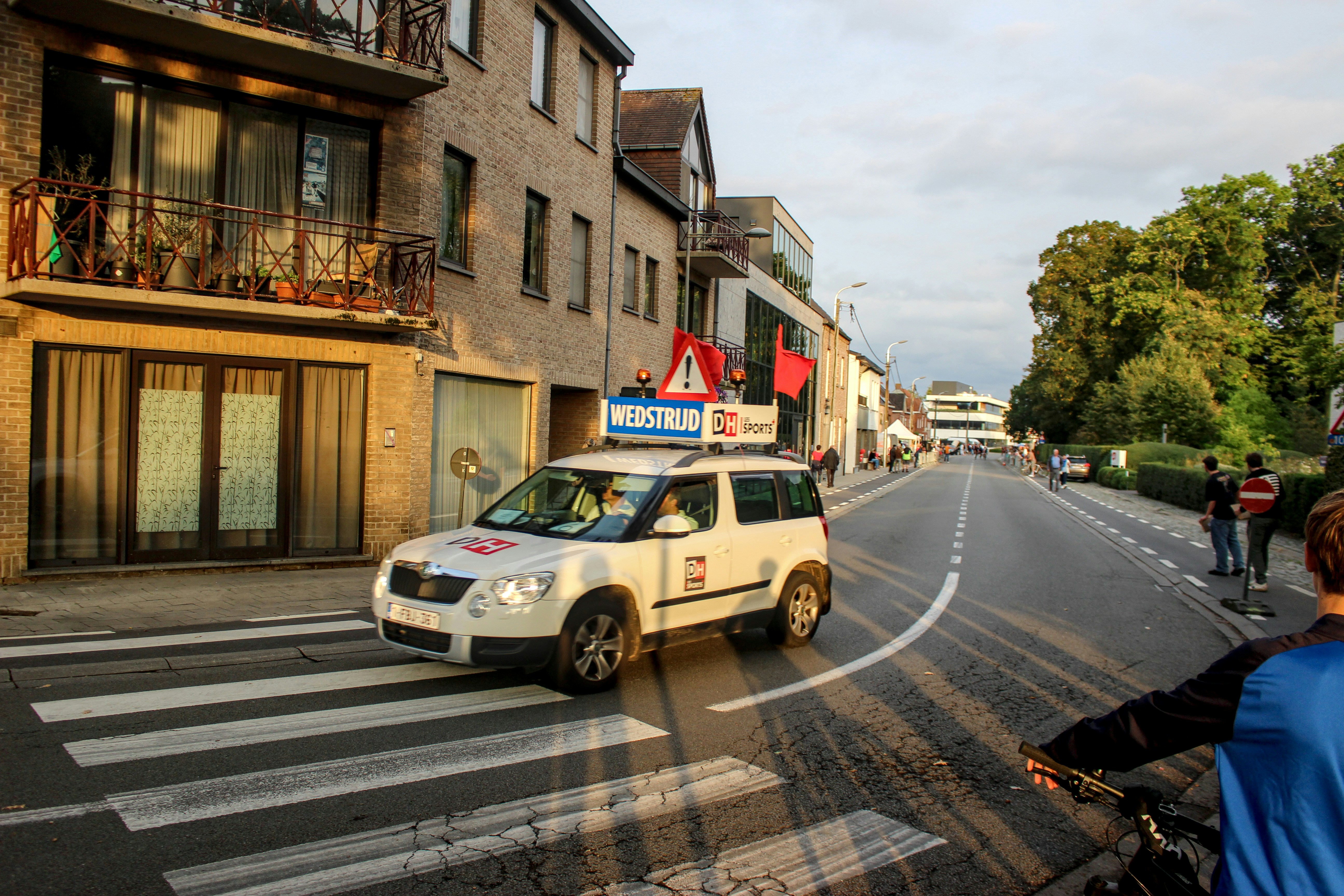 White car driving on a street with buildings.
