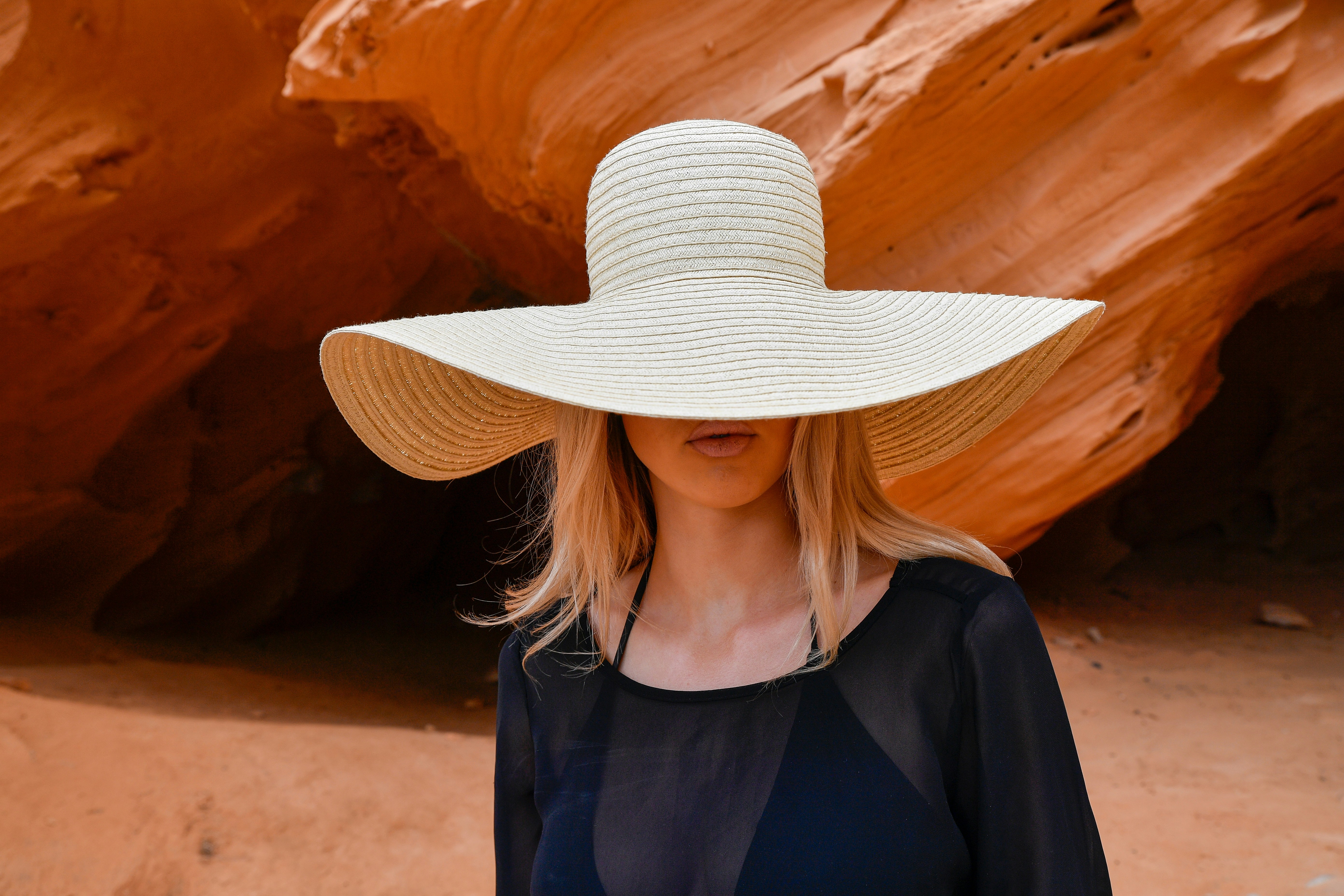 Woman in a wide-brimmed hat against rock formations