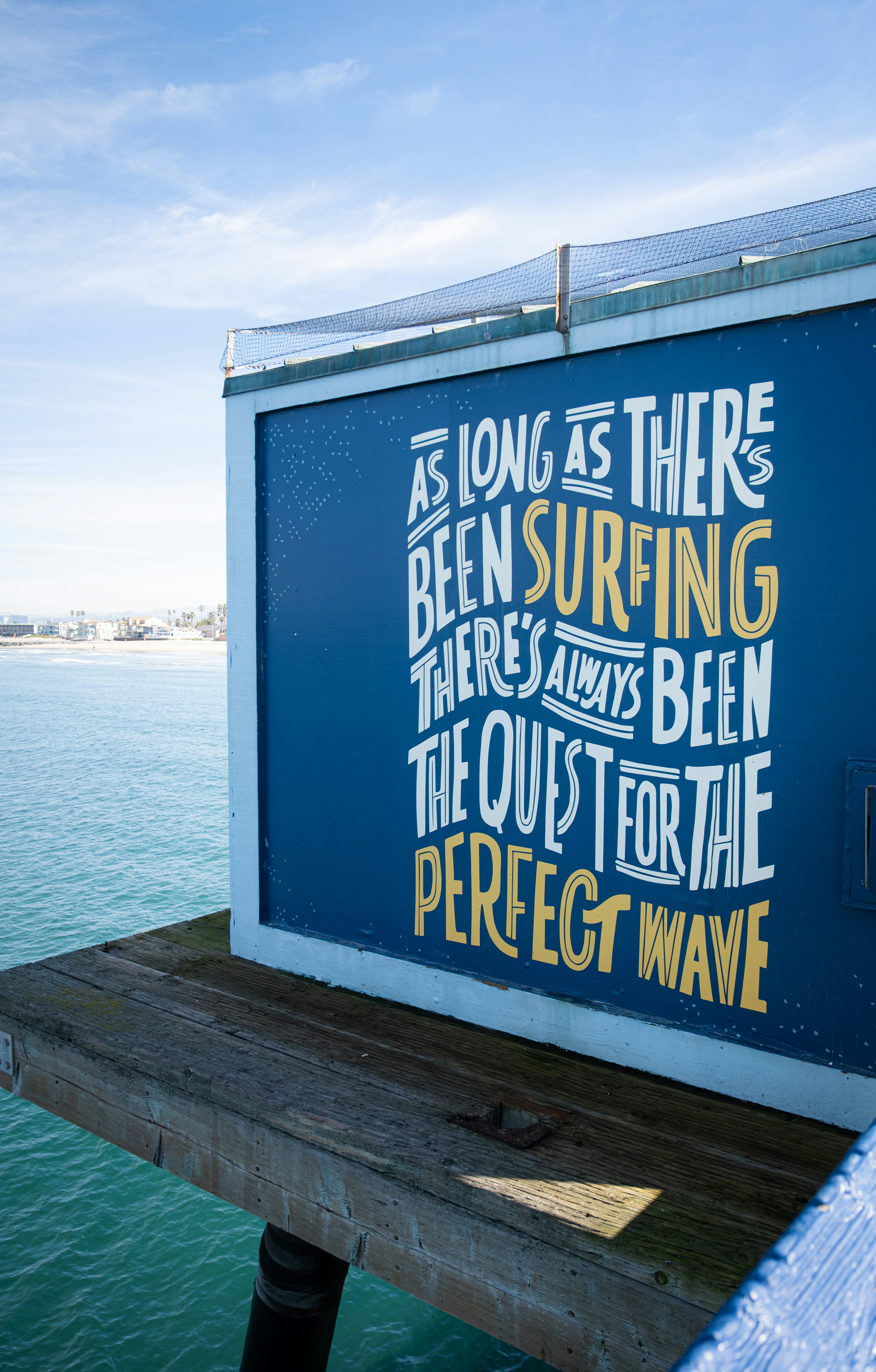 Surfing quote on a blue sign at the beach