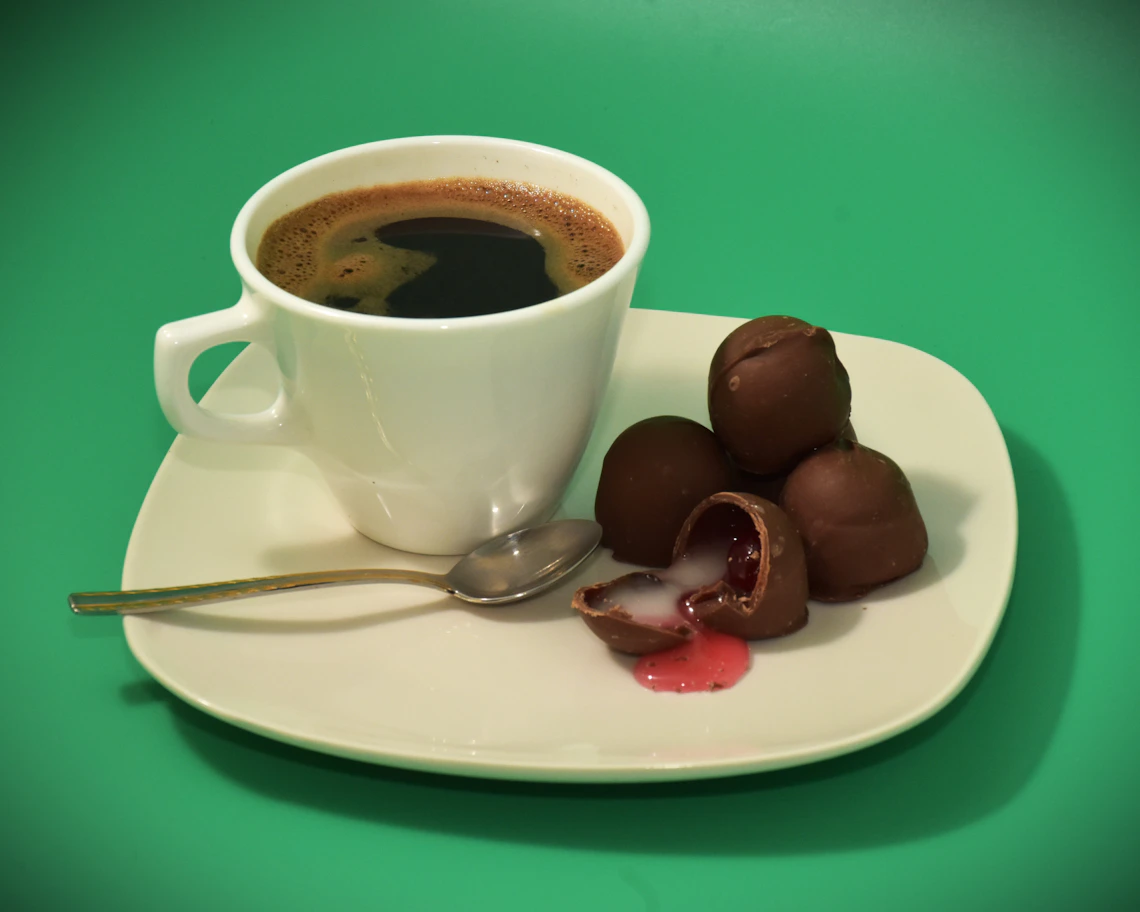 Coffee served with chocolates on a plate in an elegant tabletop setting.
