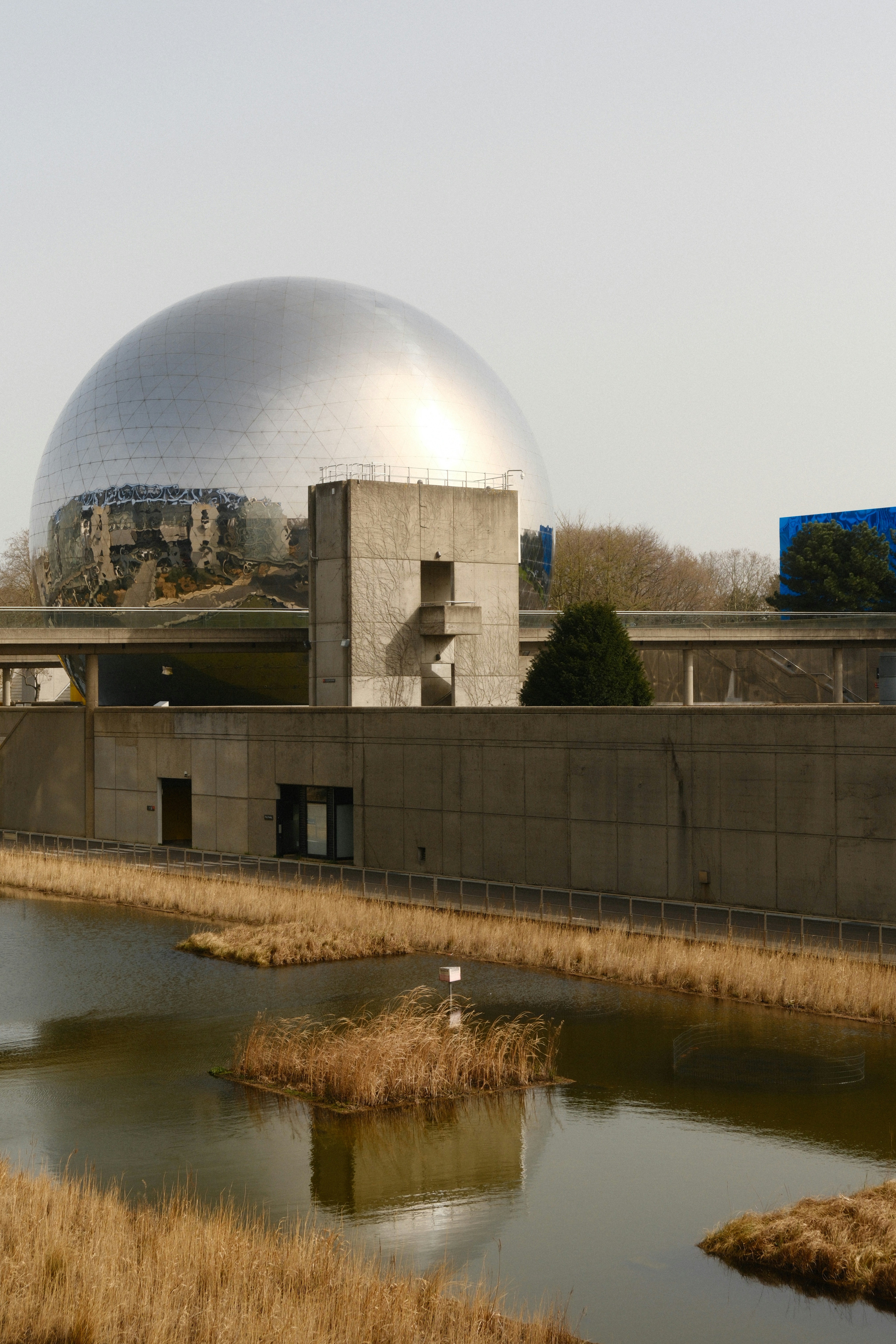 Large geodesic dome building with concrete structure and pond