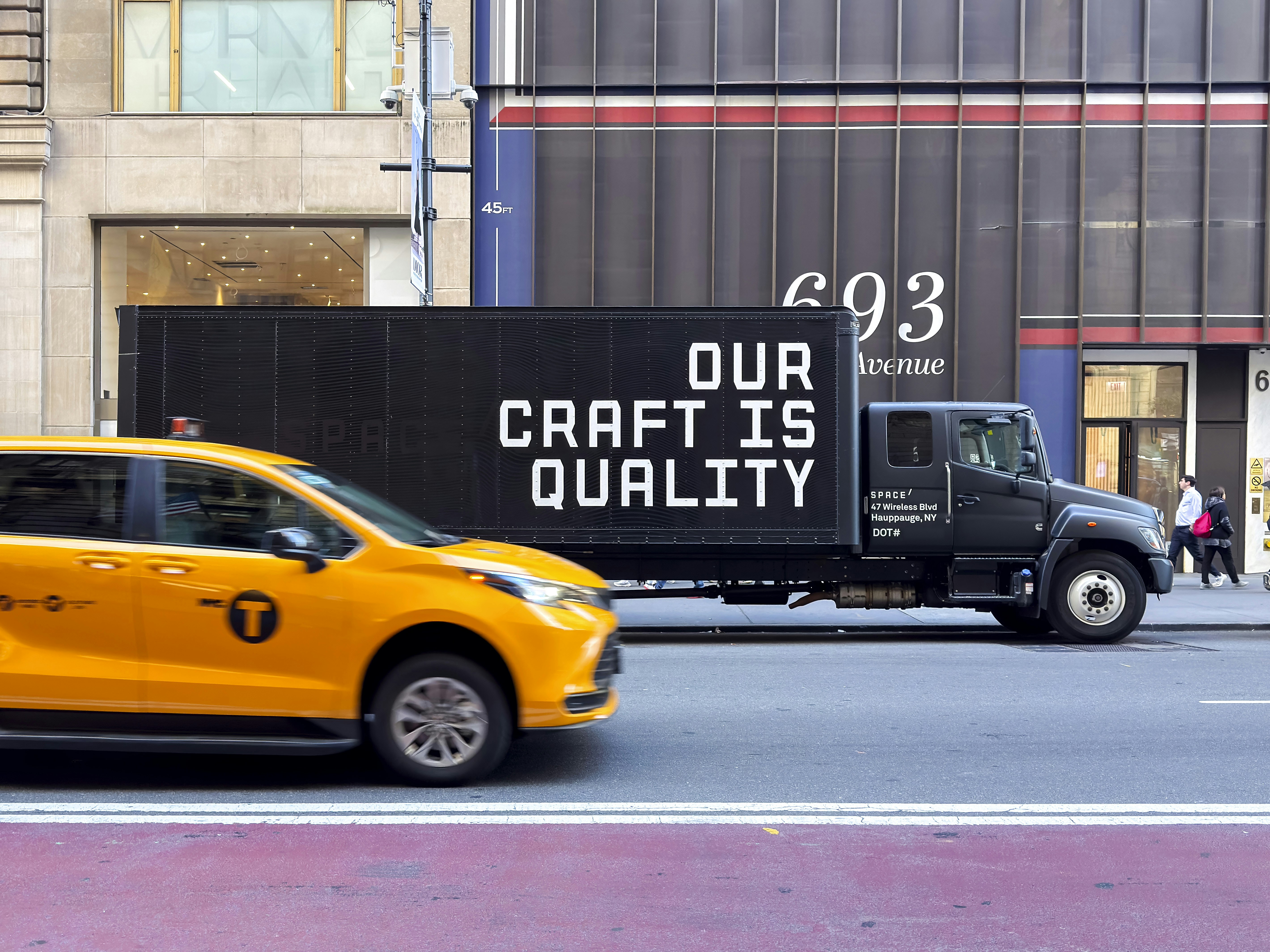 Yellow taxi and truck with text on street