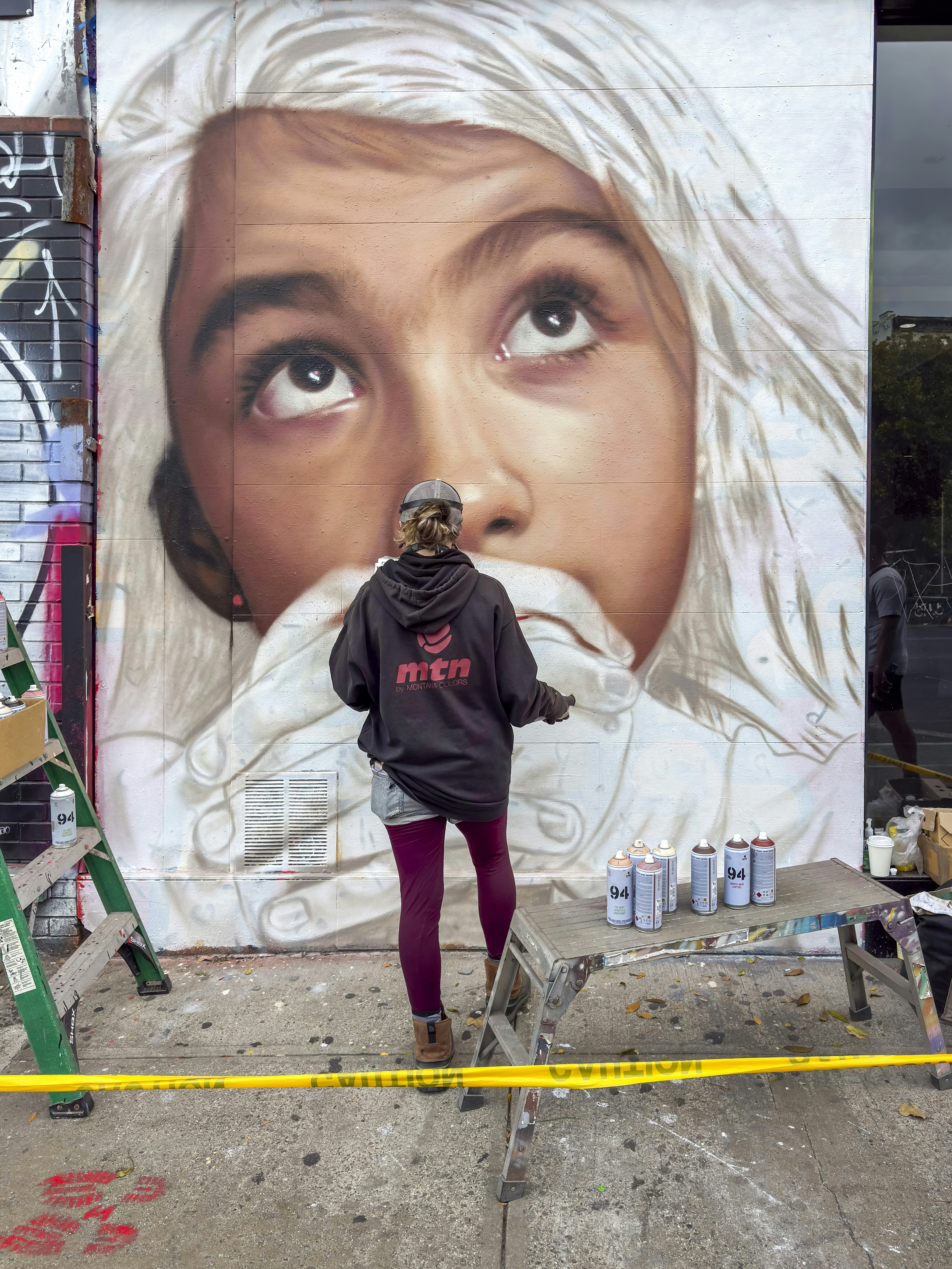 Artist paints a large mural of a child's face.