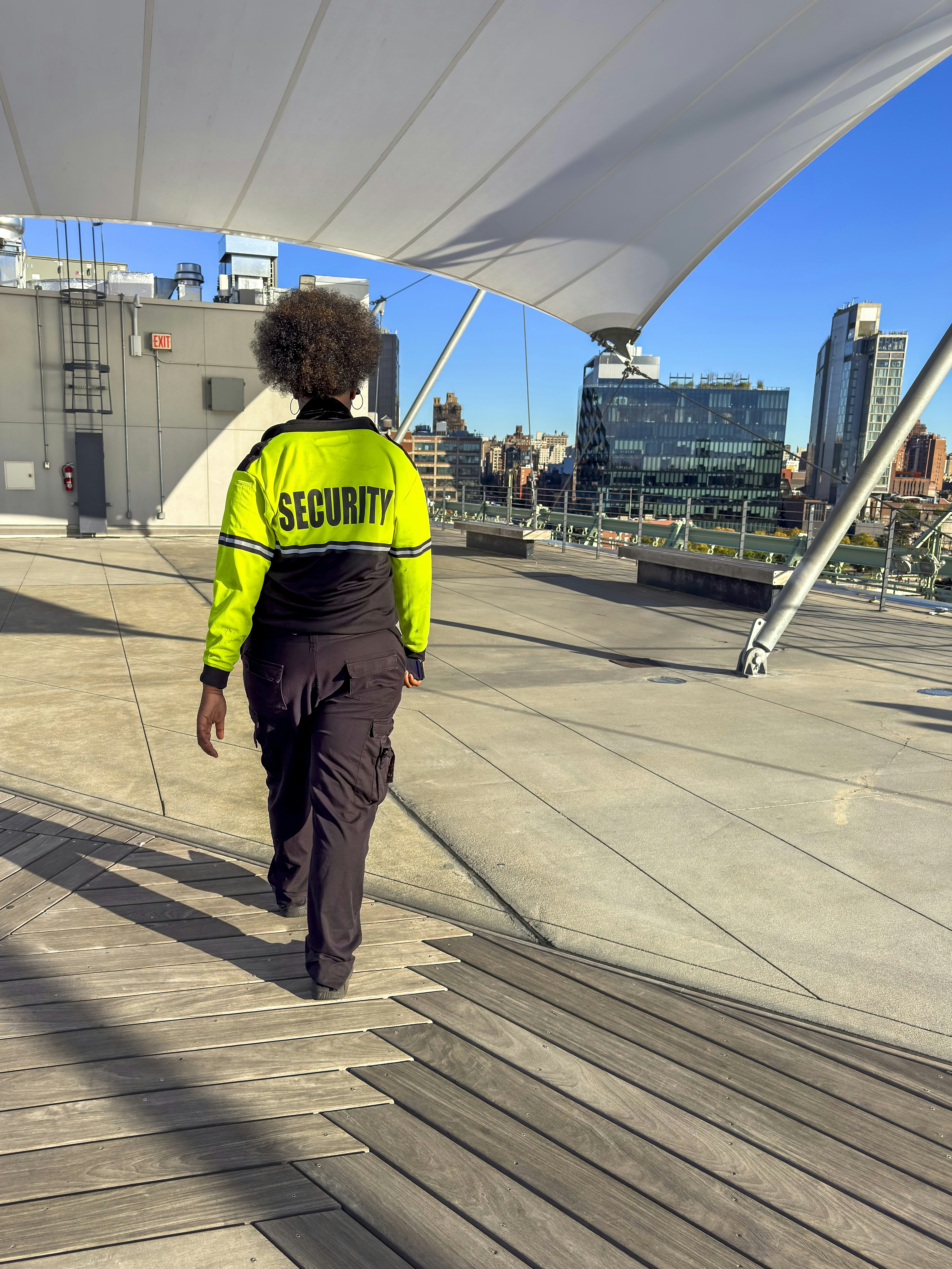 Security guard walking on a rooftop overlooking city