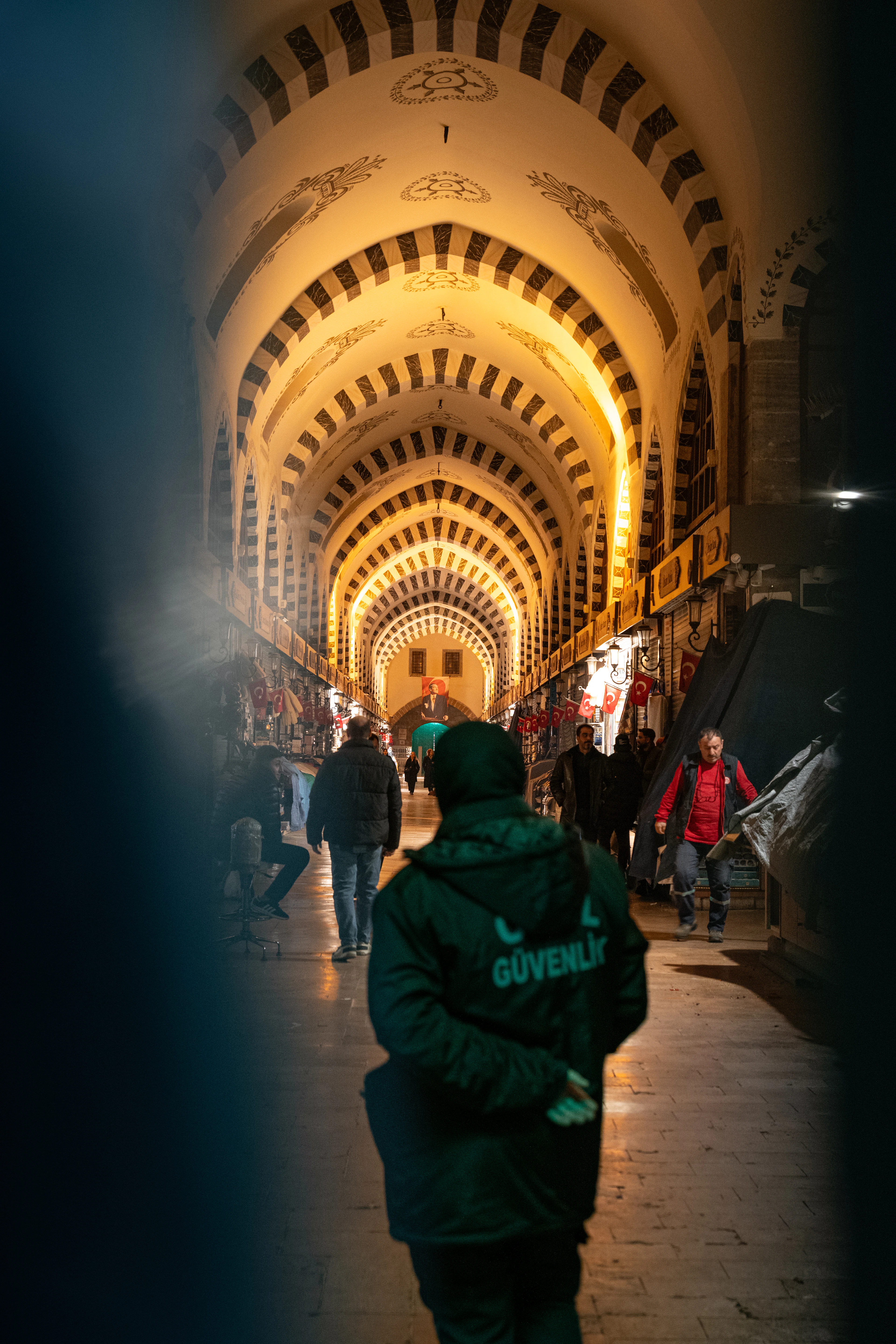 Shoppers walking through a vaulted, arched corridor of Istanbul's Grand Bazaar