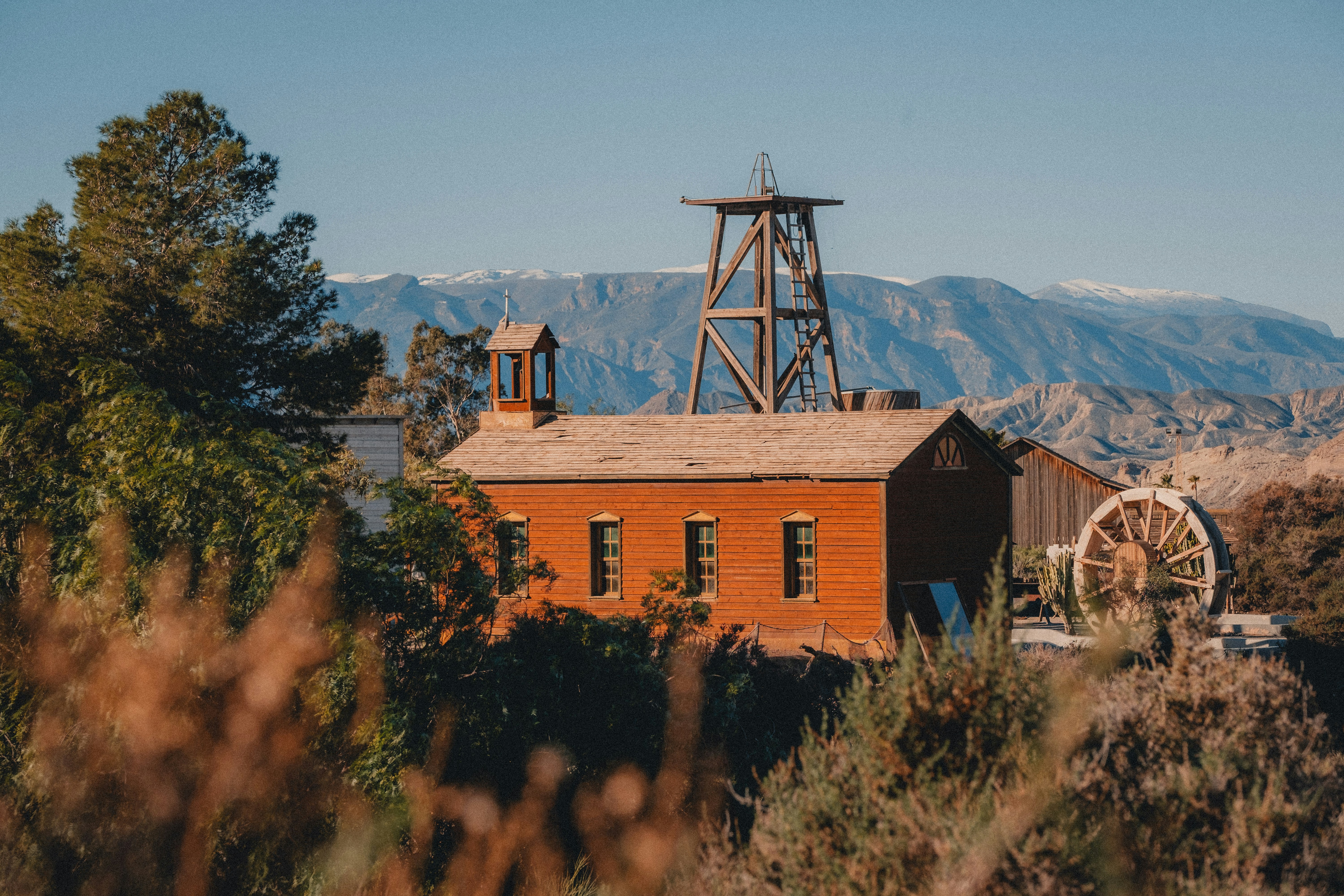 Altes Backsteingebäude mit Holzturm und Wasserrad.