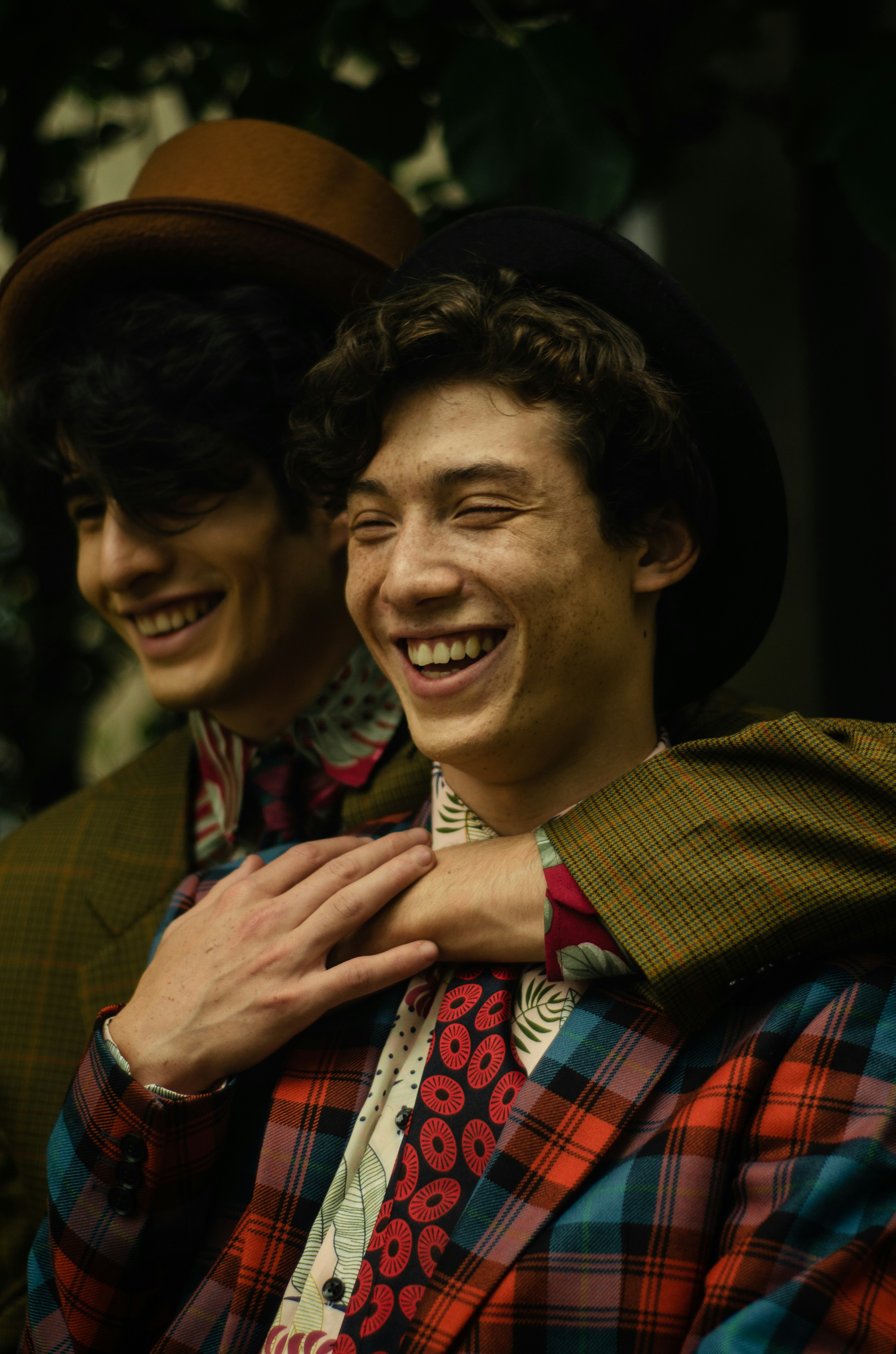 Dos jóvenes con sombreros y chaquetas coloridas riendo