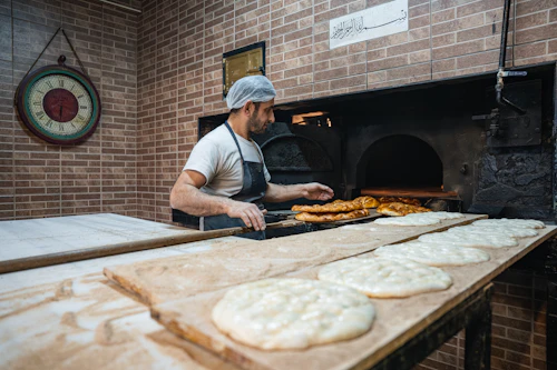 Baker placing pastries into a brick oven