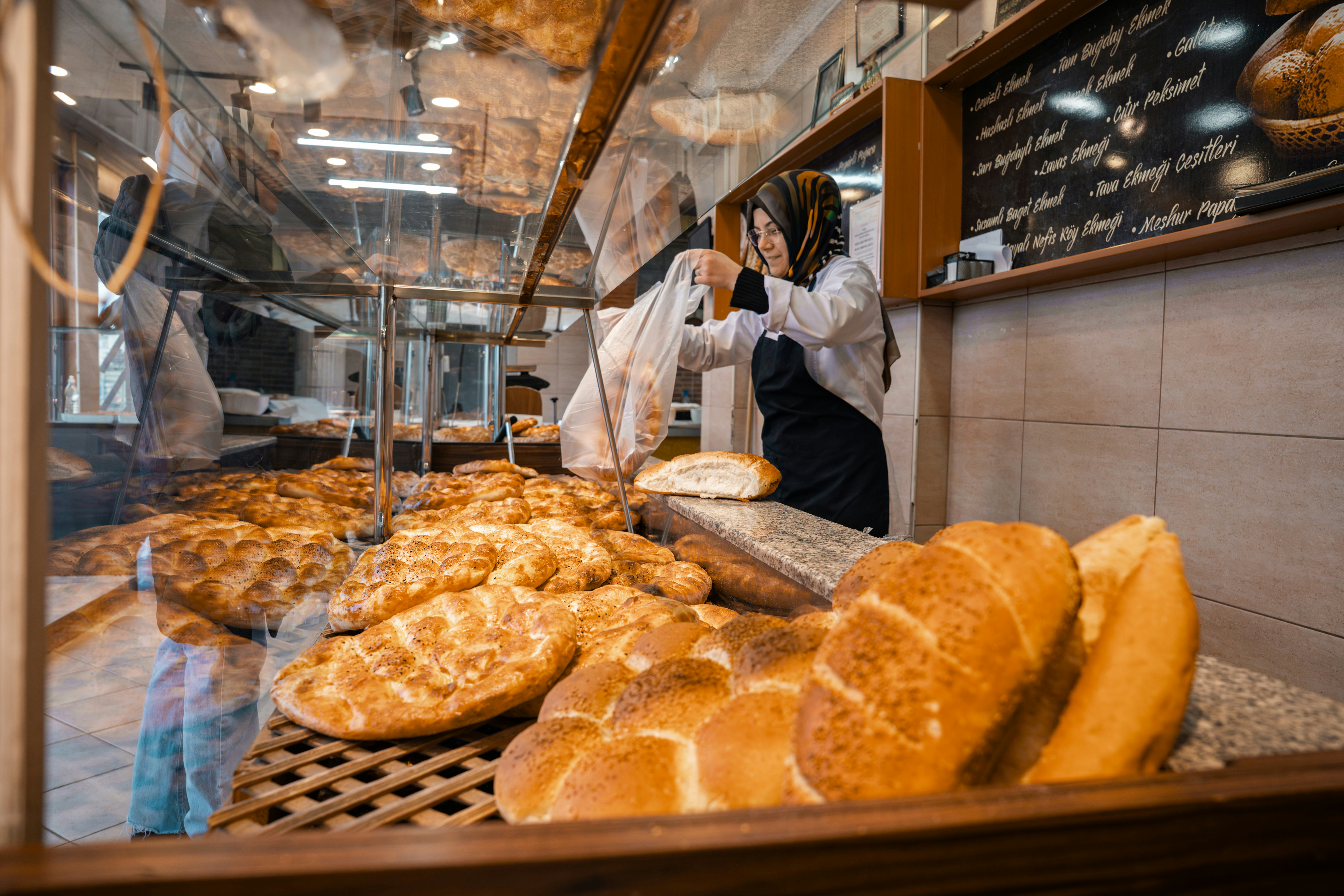 Baker arranging fresh bread in a bakery display.