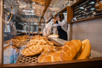 Baker arranging fresh bread in a bakery display.