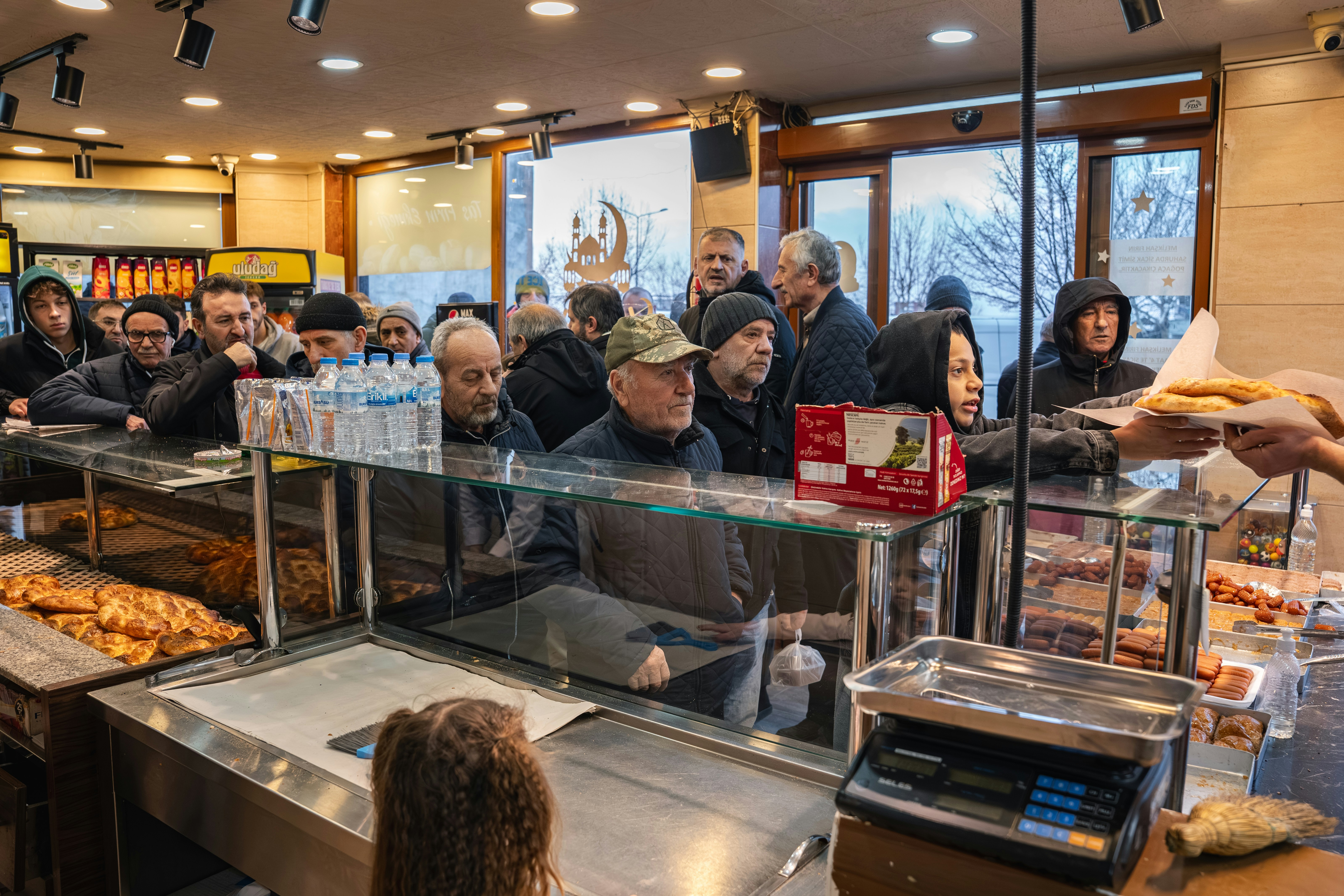 People waiting in line at a bakery counter.