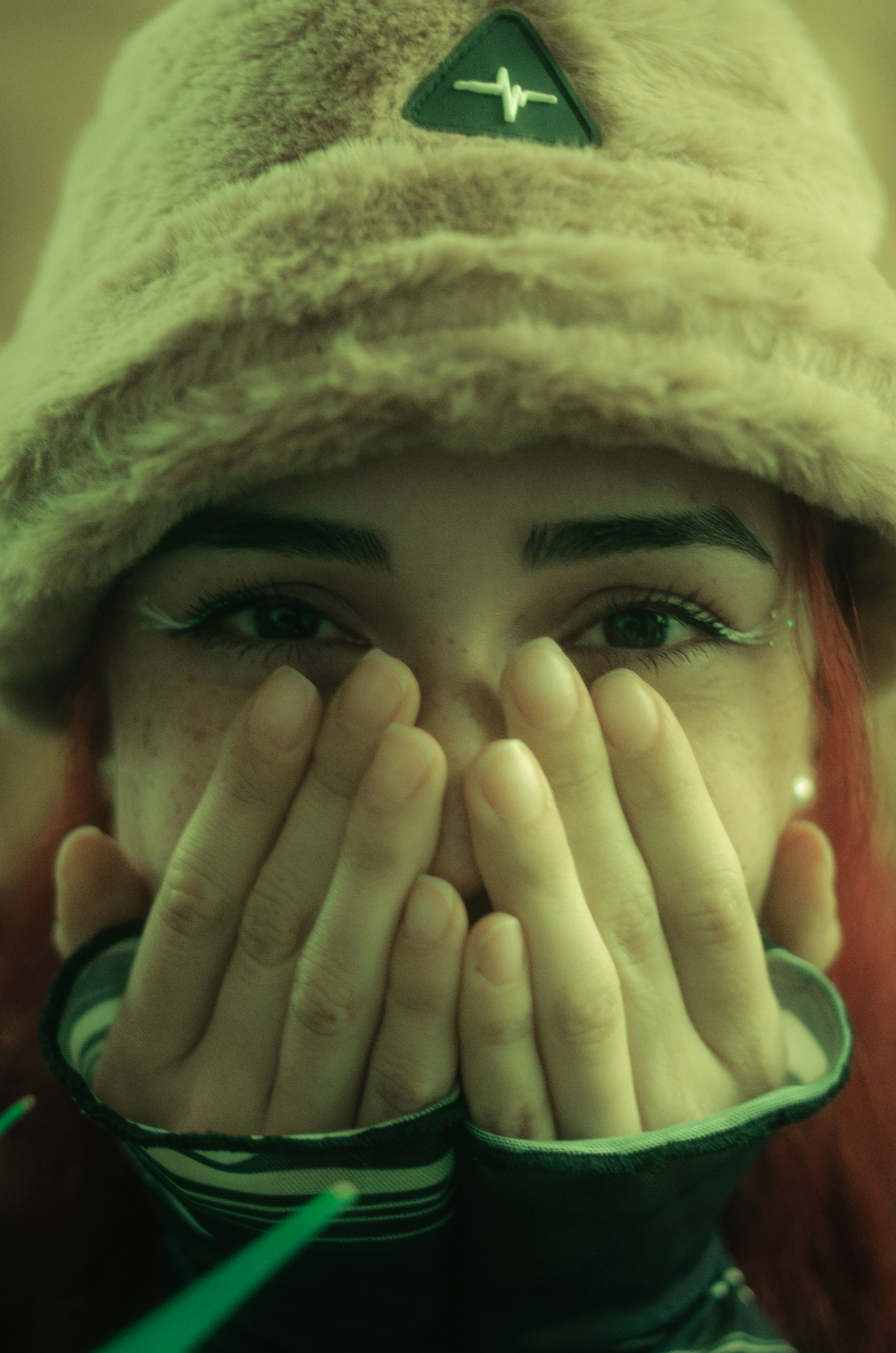 Mujer cubre la cara con las manos y lleva un sombrero peludo