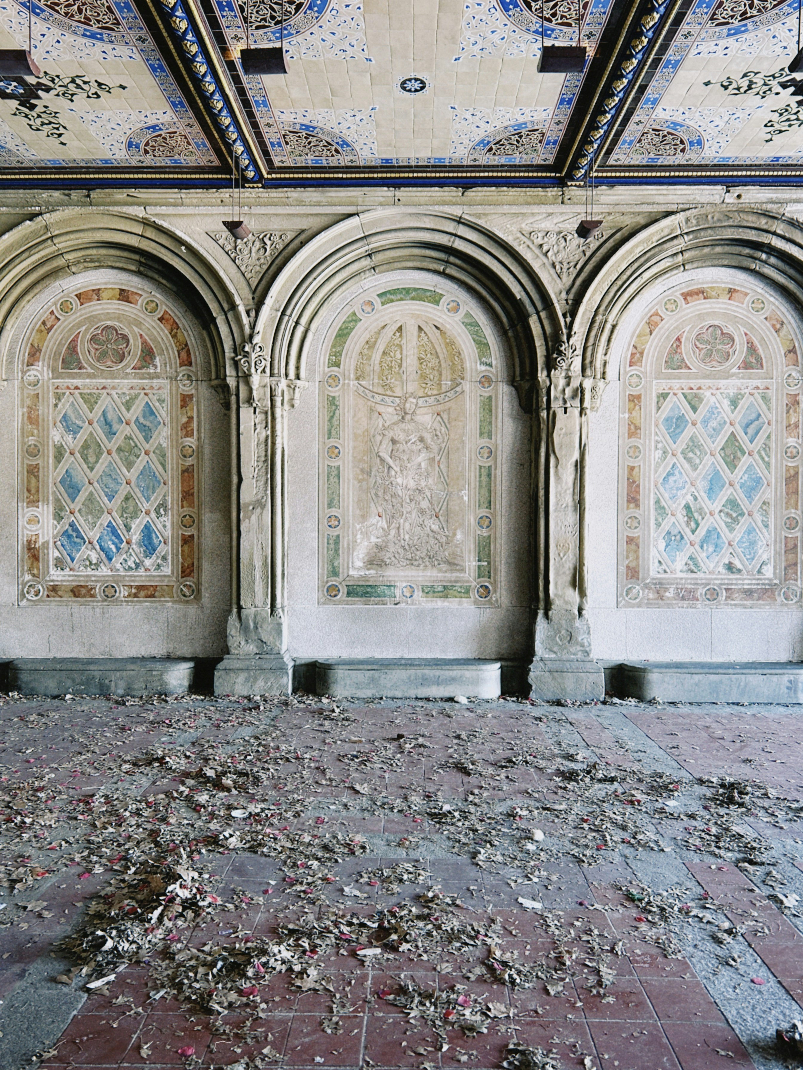 Gewölbte Nischen mit Mosaikkunst und Trümmern auf dem Boden