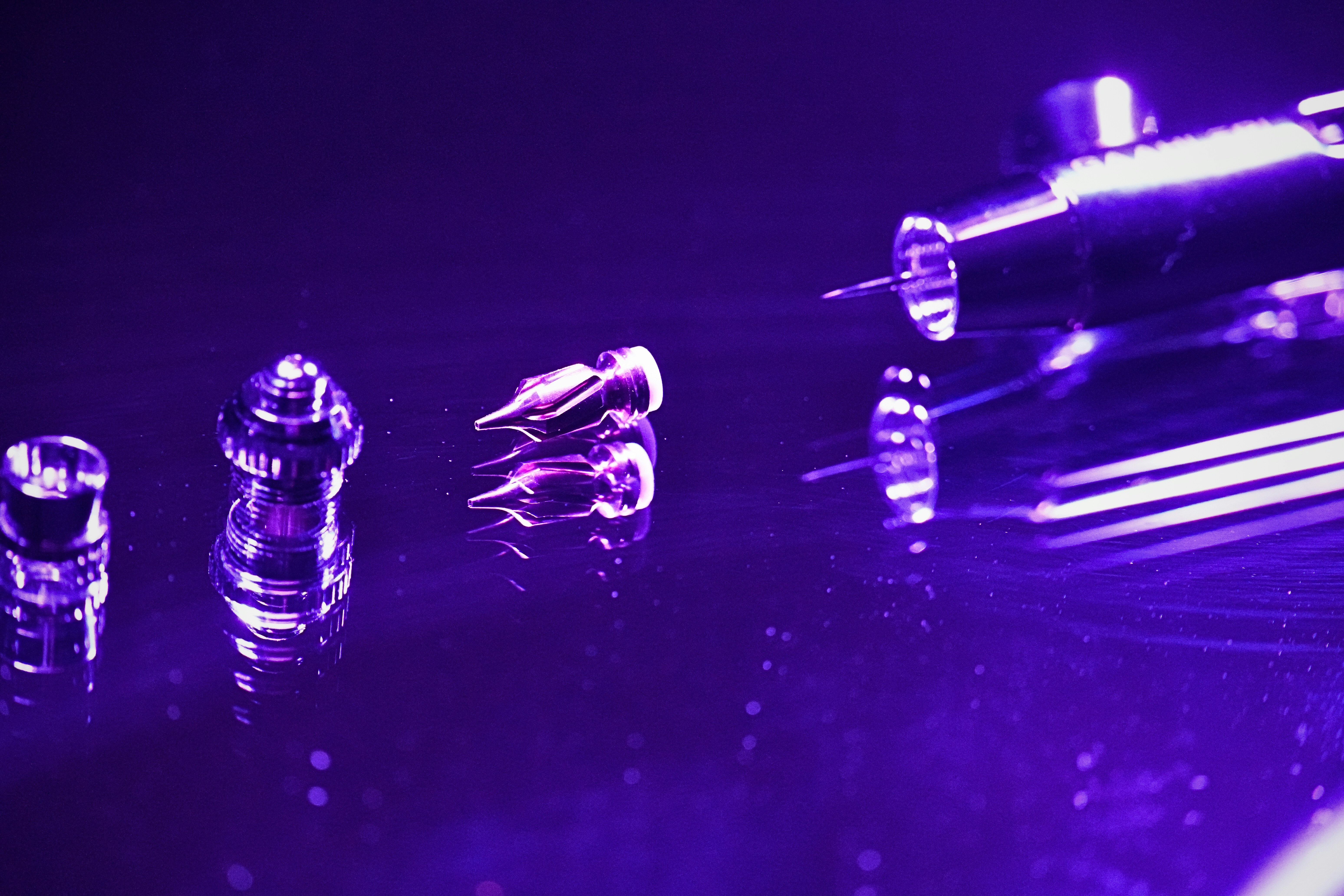 Small glass objects with purple lighting on reflective surface