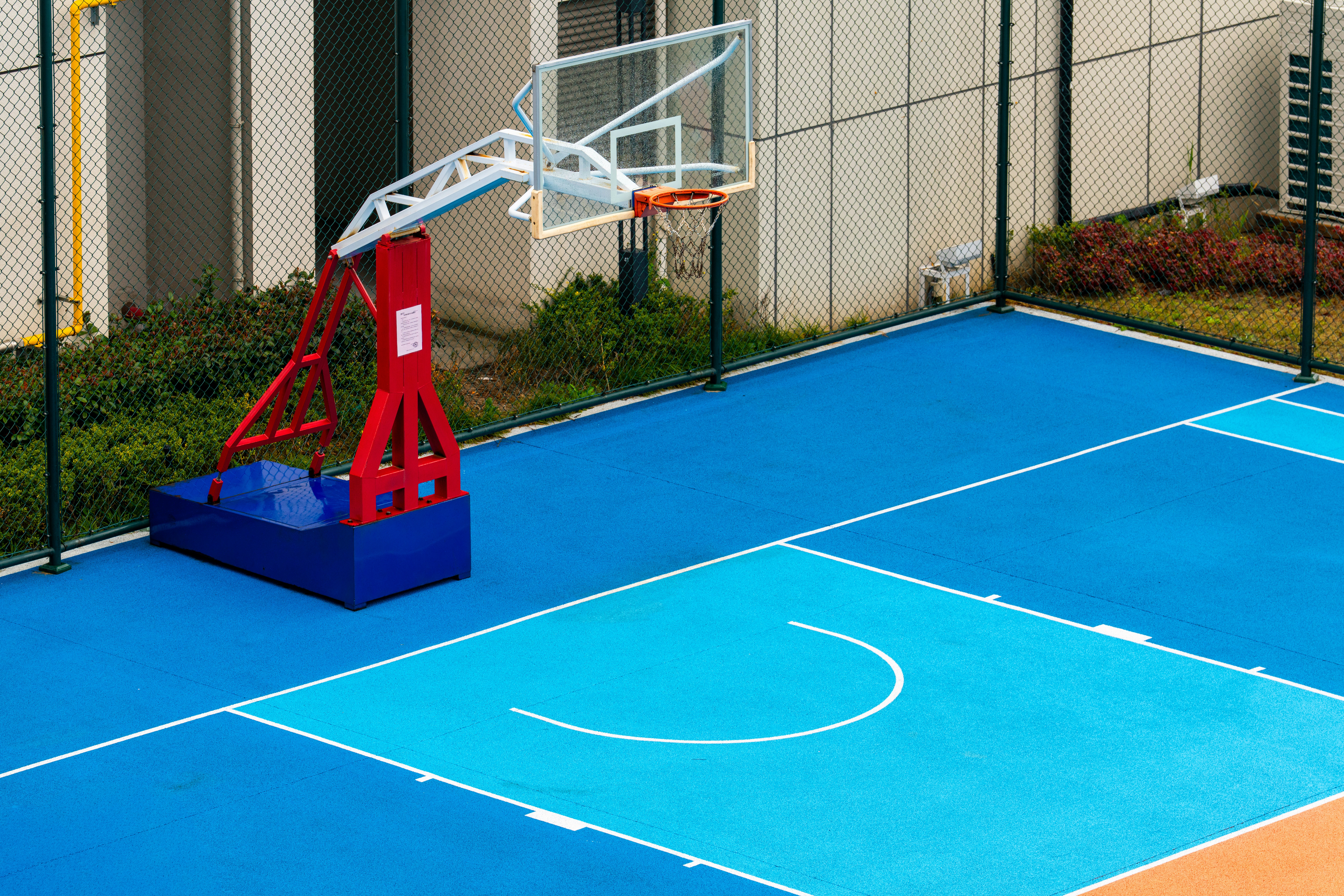 A colorful outdoor basketball court with a hoop.