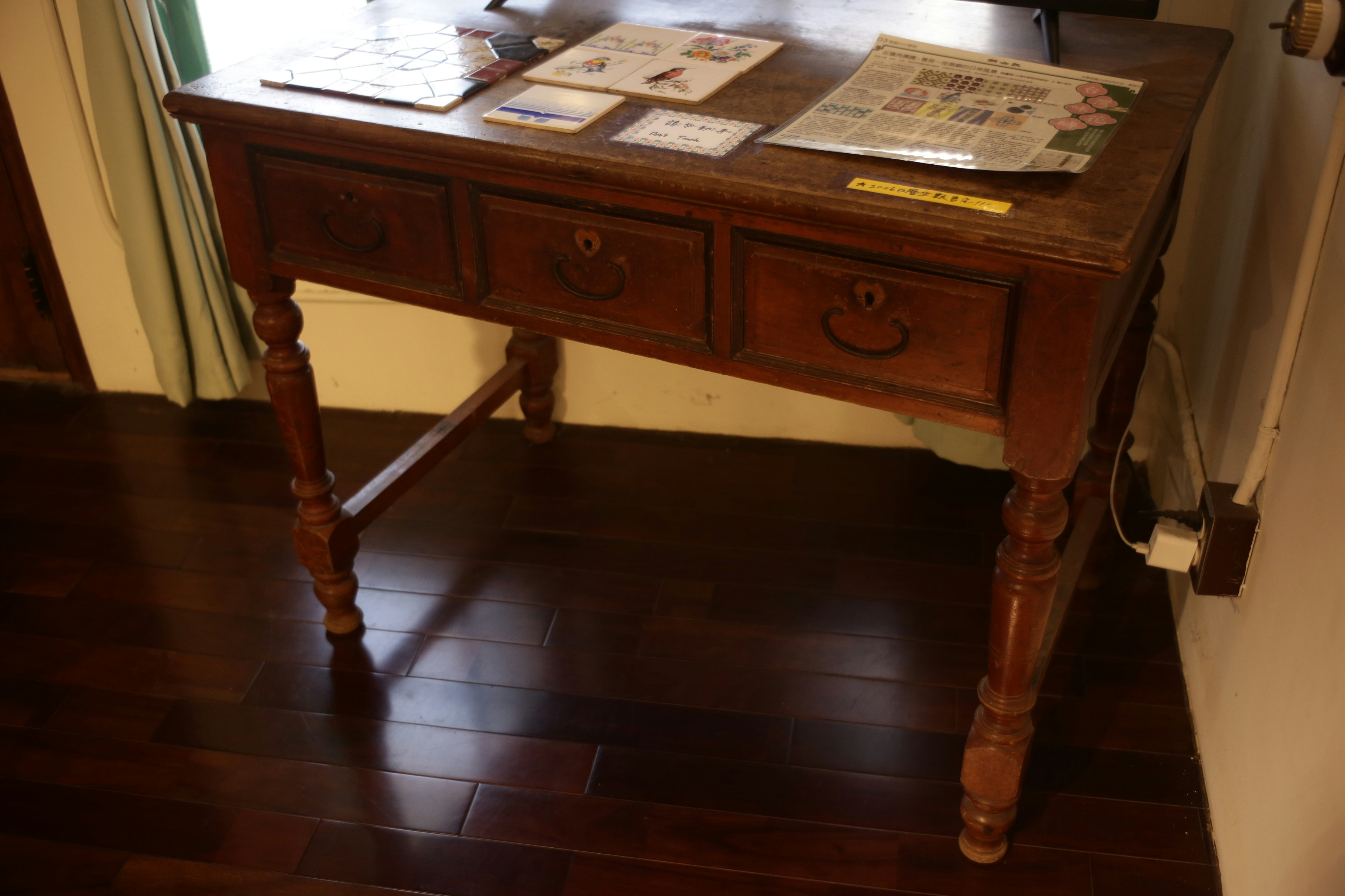 Antiker Holzschreibtisch mit drei Schubladen und kunstvollen Been.