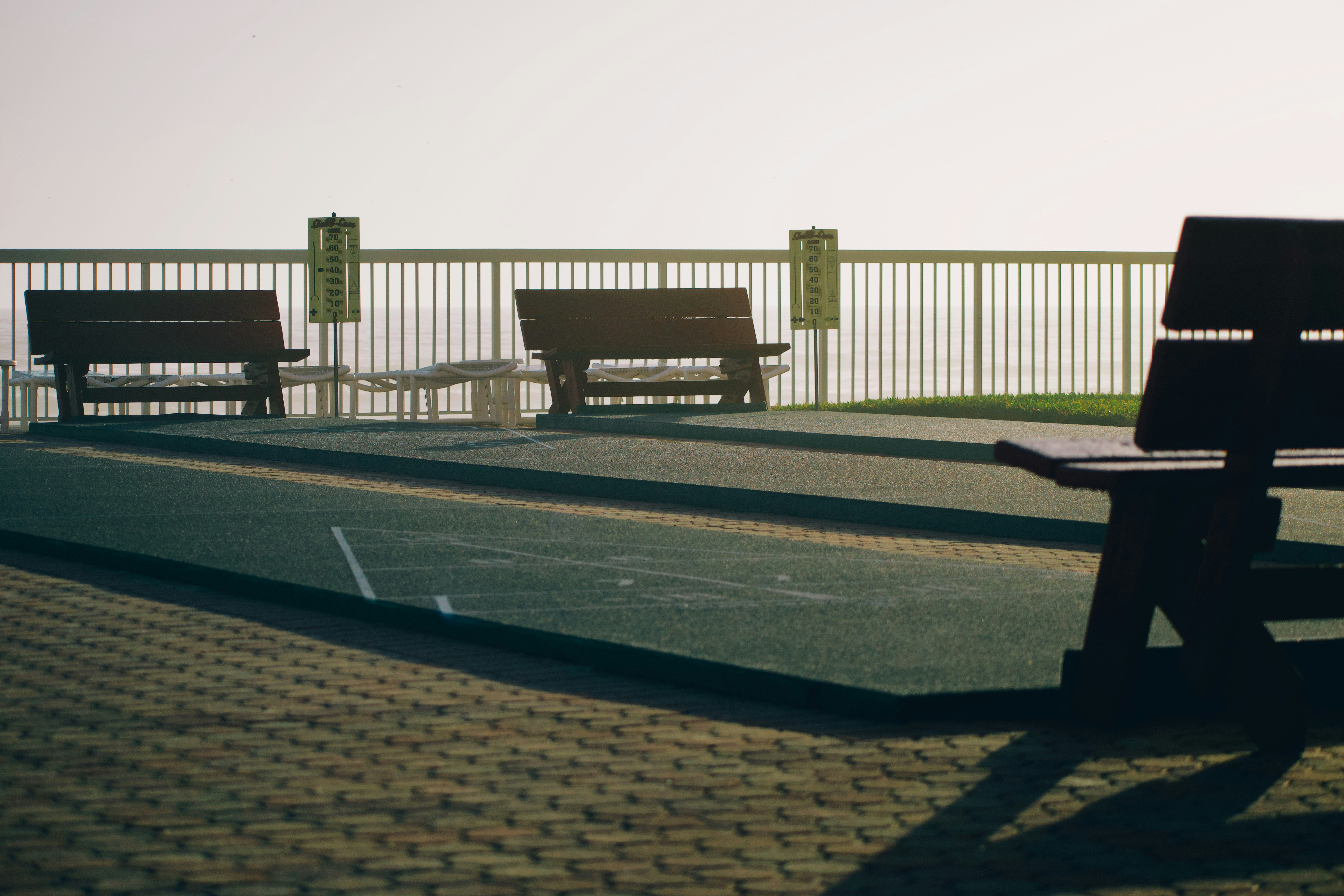 手すりに面した空の公園ベンチが3つ、霧の背景に面している。