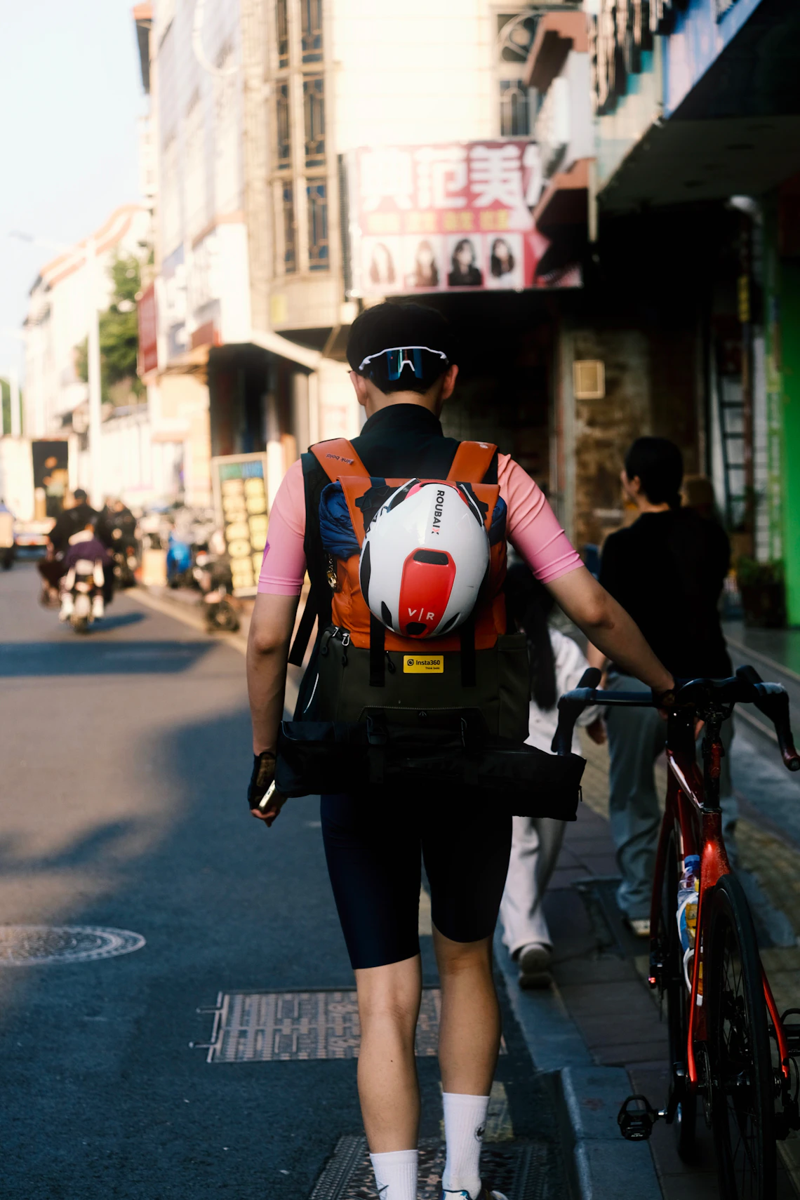 Helmeted cyclist carrying a backpack while walking along an urban street